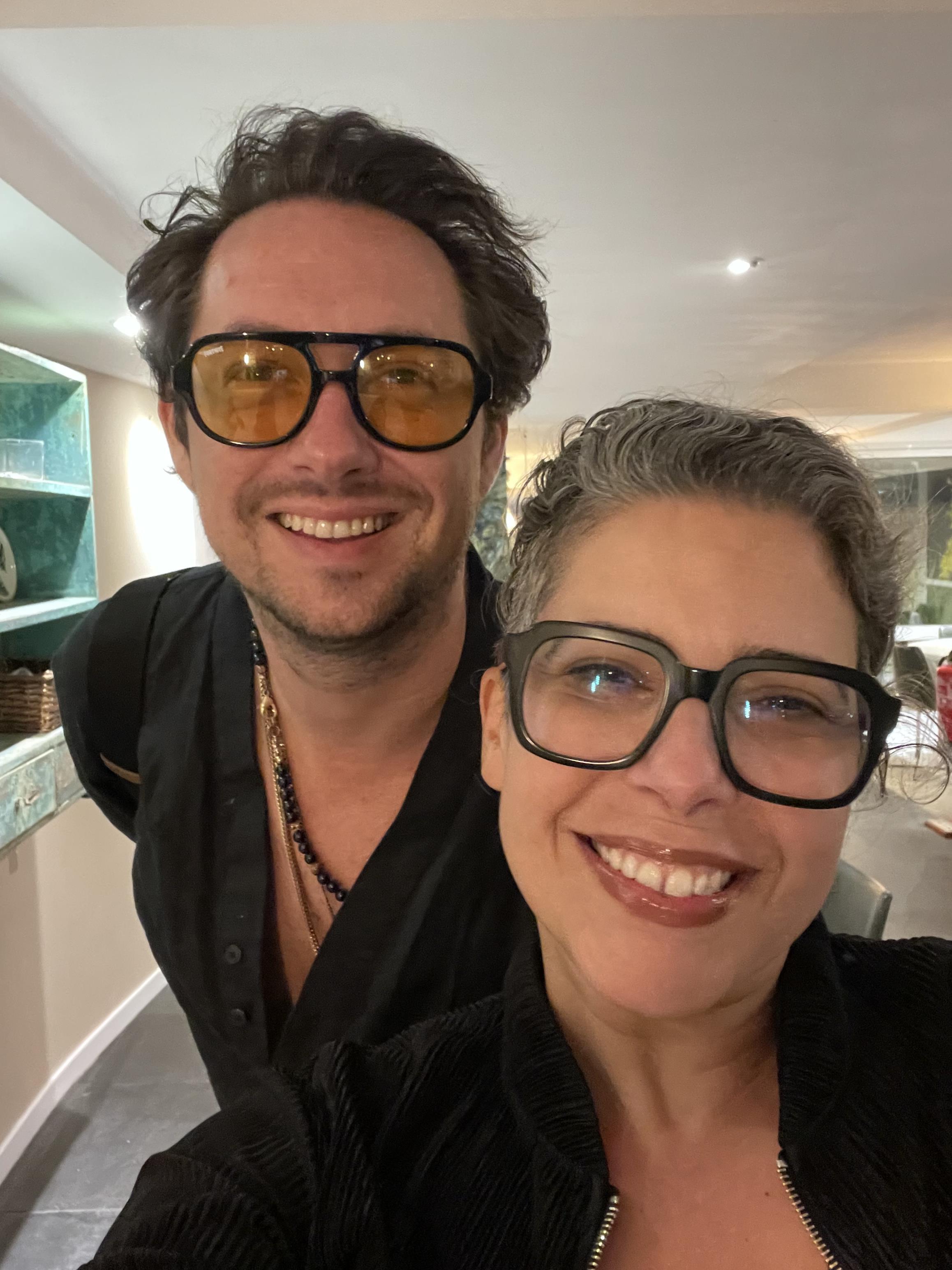 Two friends smile together in a chic indoor environment, enjoying their time at a social event.