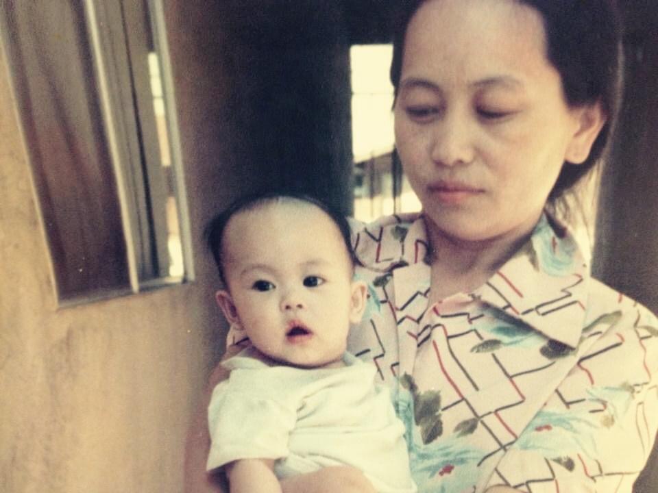 A woman gently holds a baby while standing in a cozy, sunlit doorway.