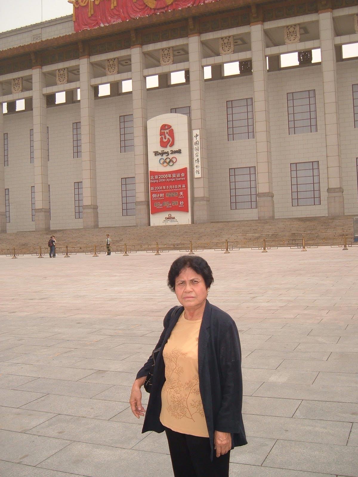 An older woman stands confidently outside the National Museum of China, enjoying her visit.
