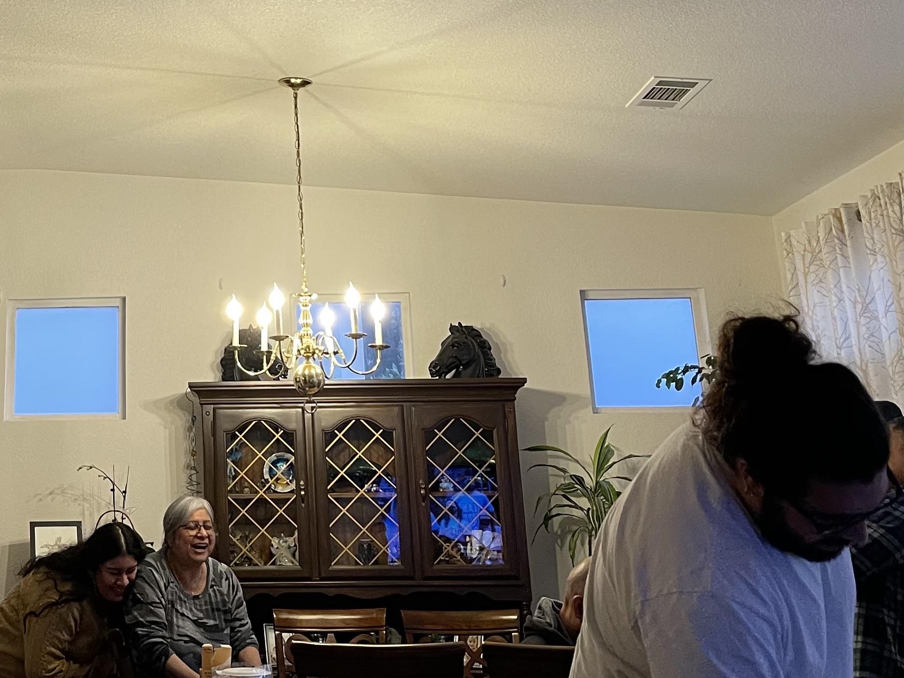 People enjoy each other's company in a cozy living room as evening descends outside.