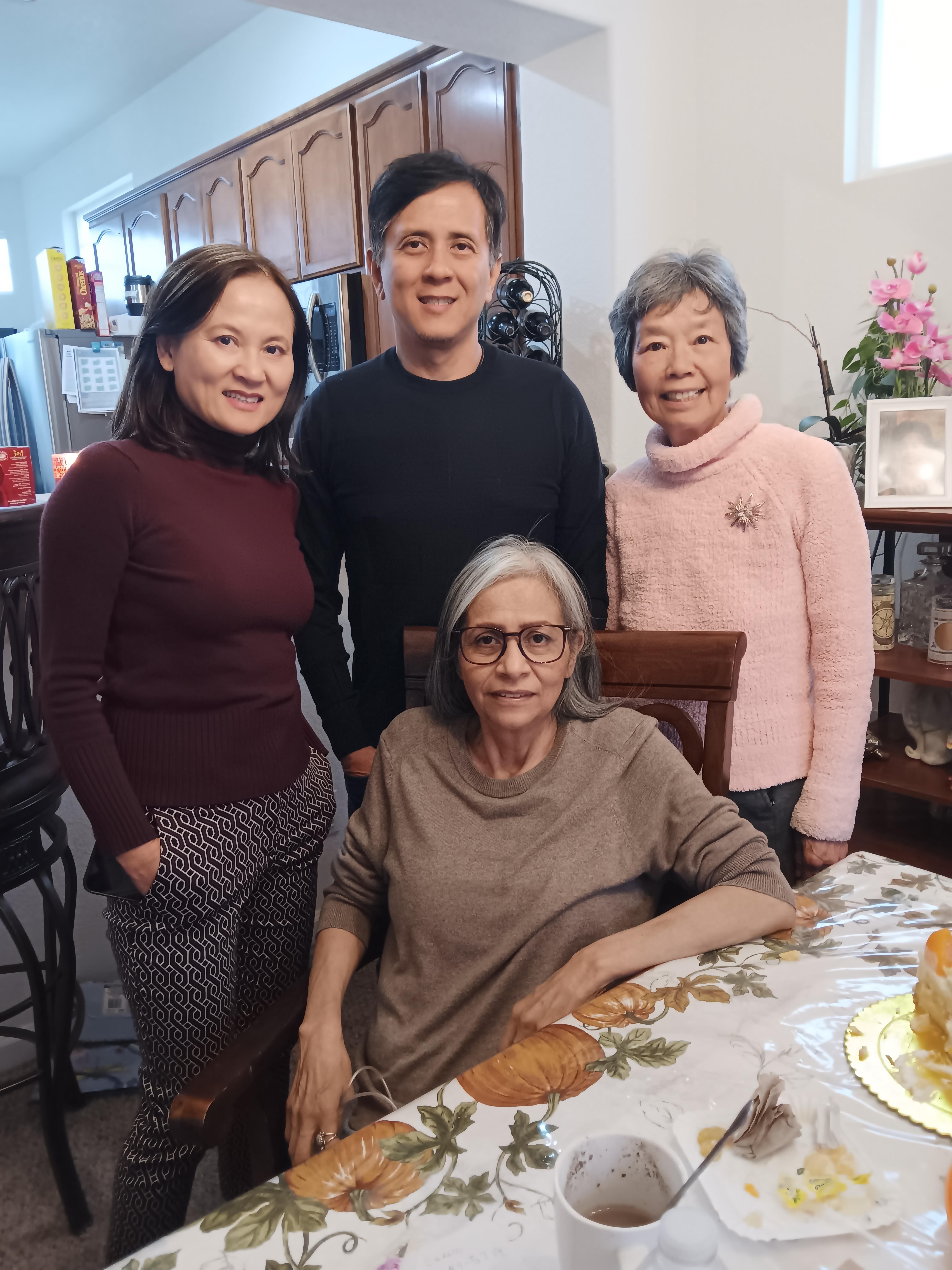 Four family members gather around a table, enjoying each other's company in a warm atmosphere.