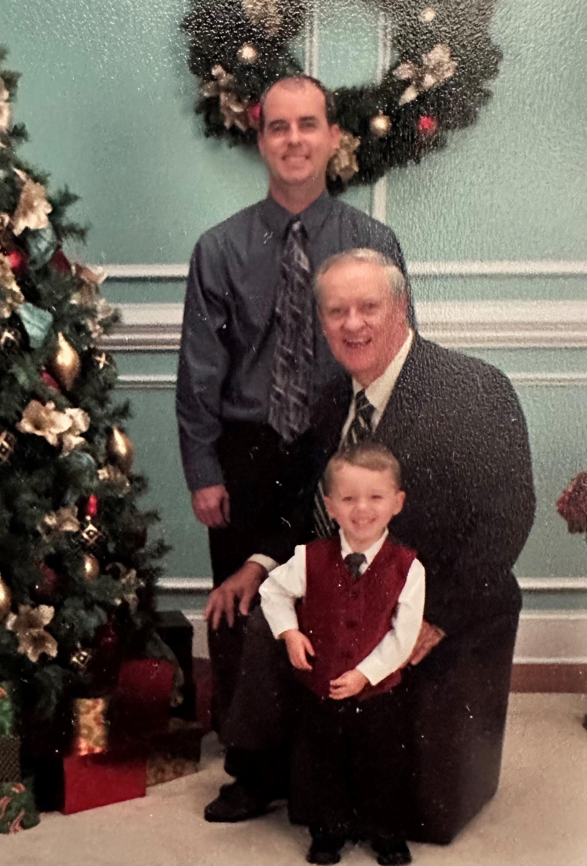Three generations gather by a decorated Christmas tree, sharing smiles and cheer.