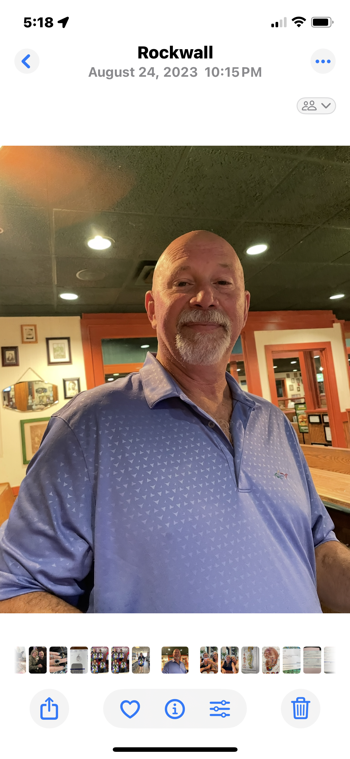 A man with a friendly smile stands casually in a vibrant restaurant with lively decor.