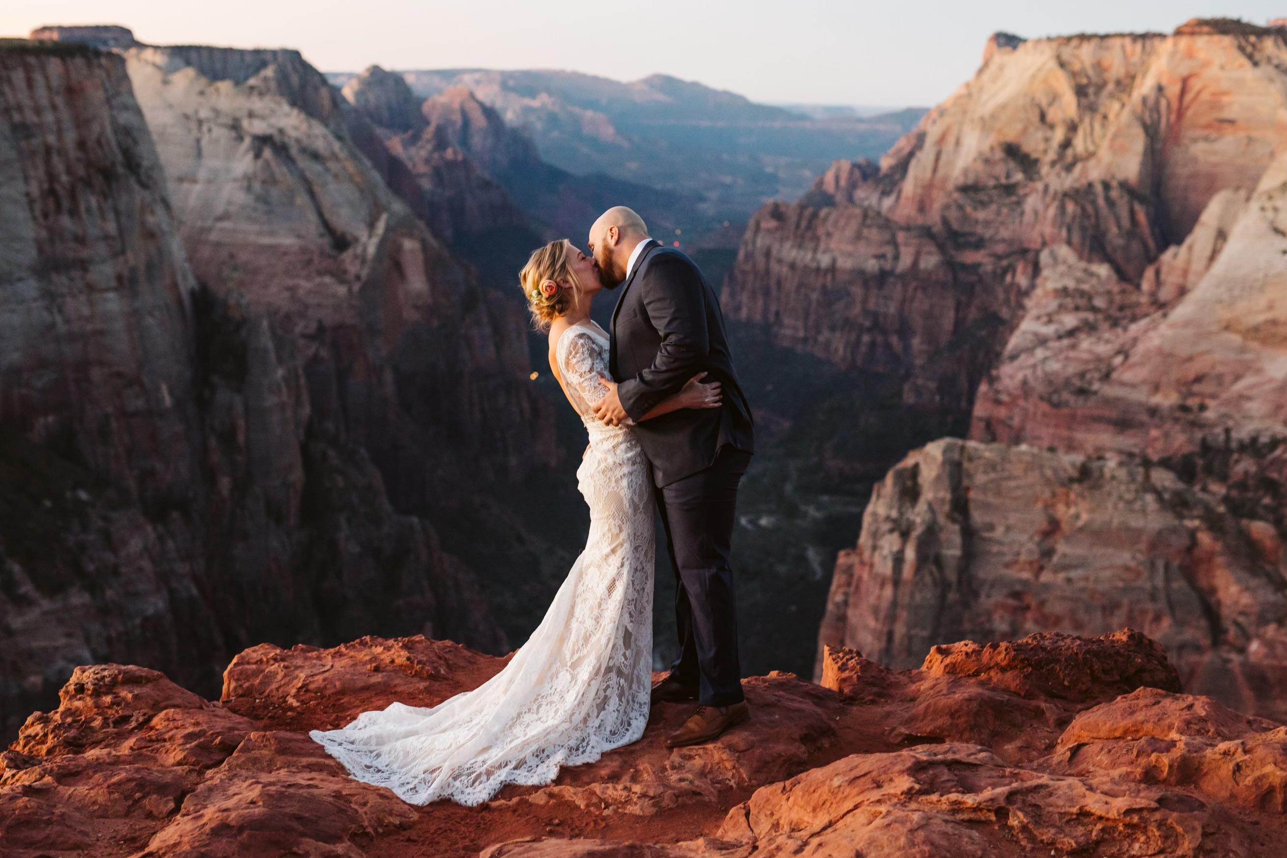 A couple shares a kiss while surrounded by breathtaking canyon views at sunset.
