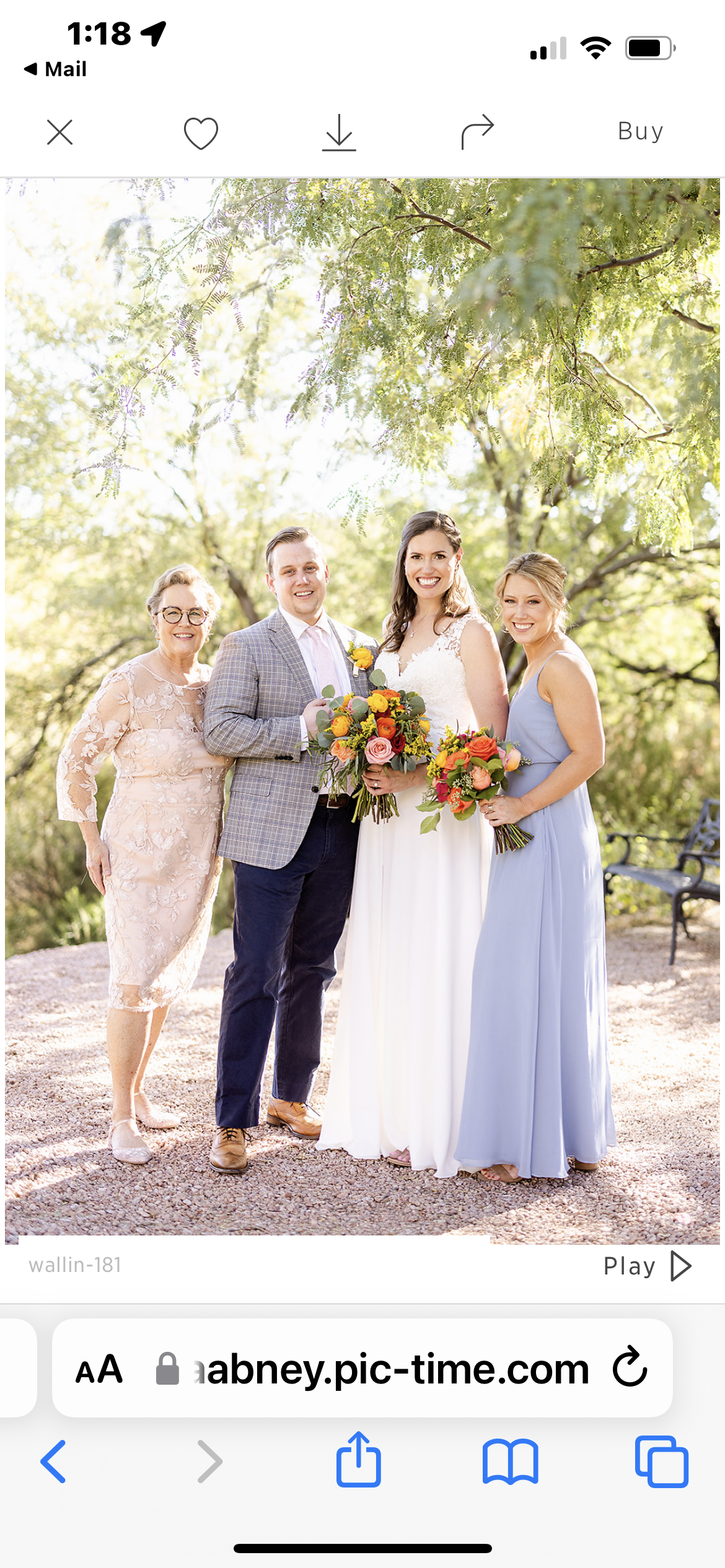 A joyful wedding party poses outside in elegant attire with vibrant flowers.