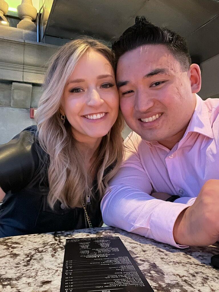 A couple smiles together at a restaurant, united by a shared menu and relaxed atmosphere.