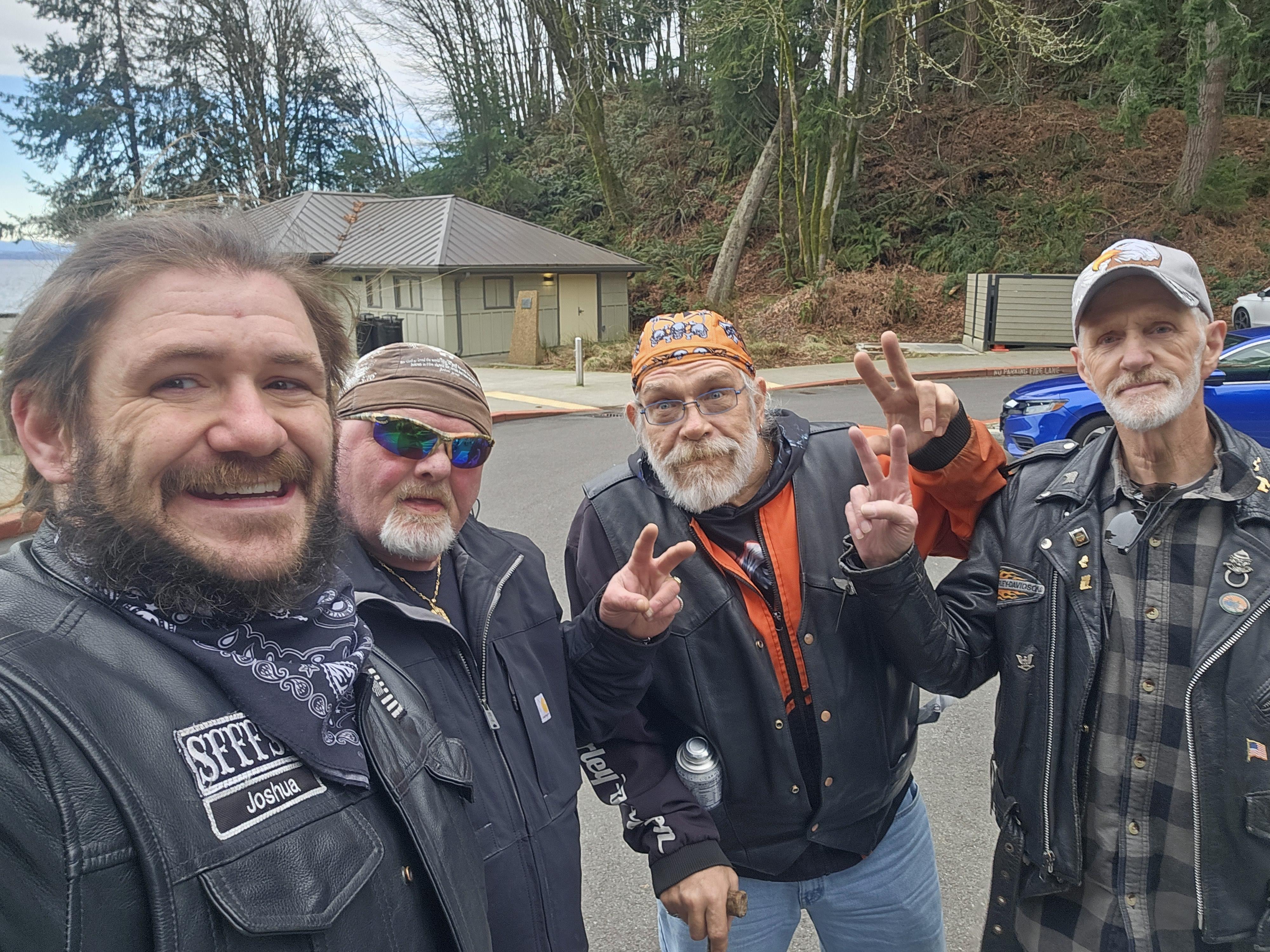 Four men in leather jackets gather for a selfie, sharing smiles and bond during their trip.