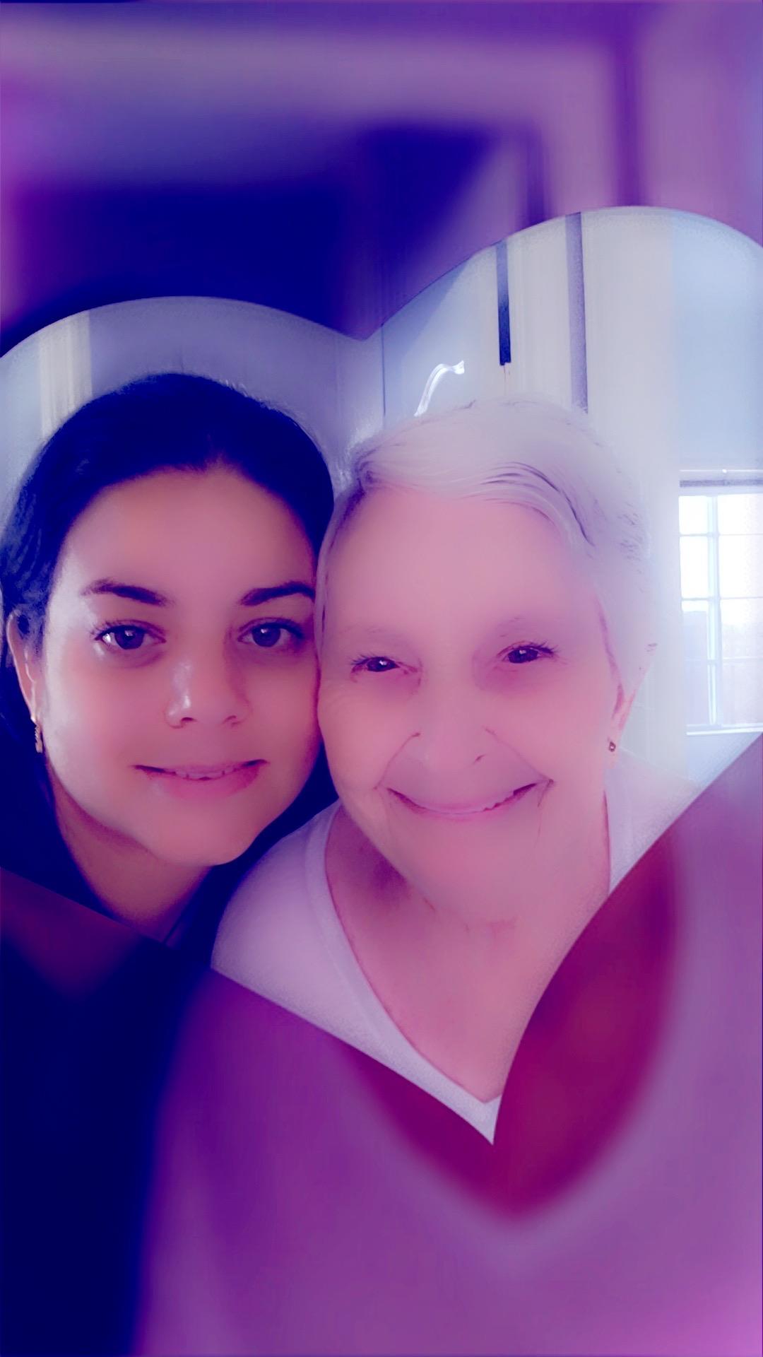 Two women share a warm embrace and smiles in a welcoming indoor environment filled with warmth.