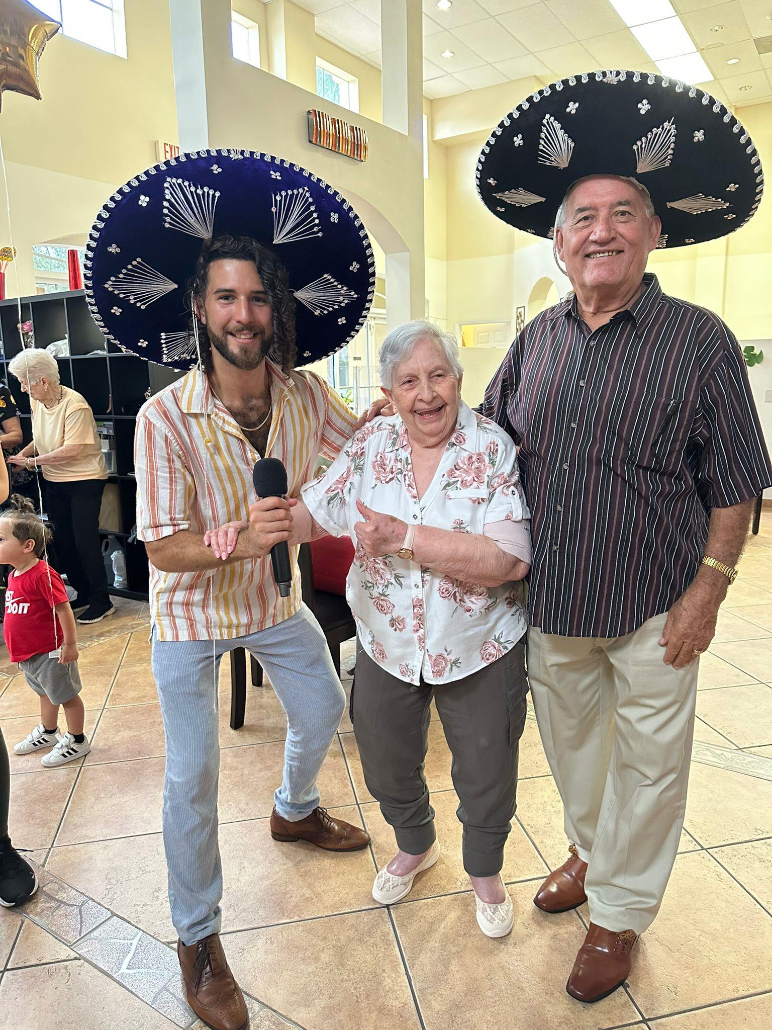 Three cheerful individuals, including an elderly couple, enjoy a festive moment together.