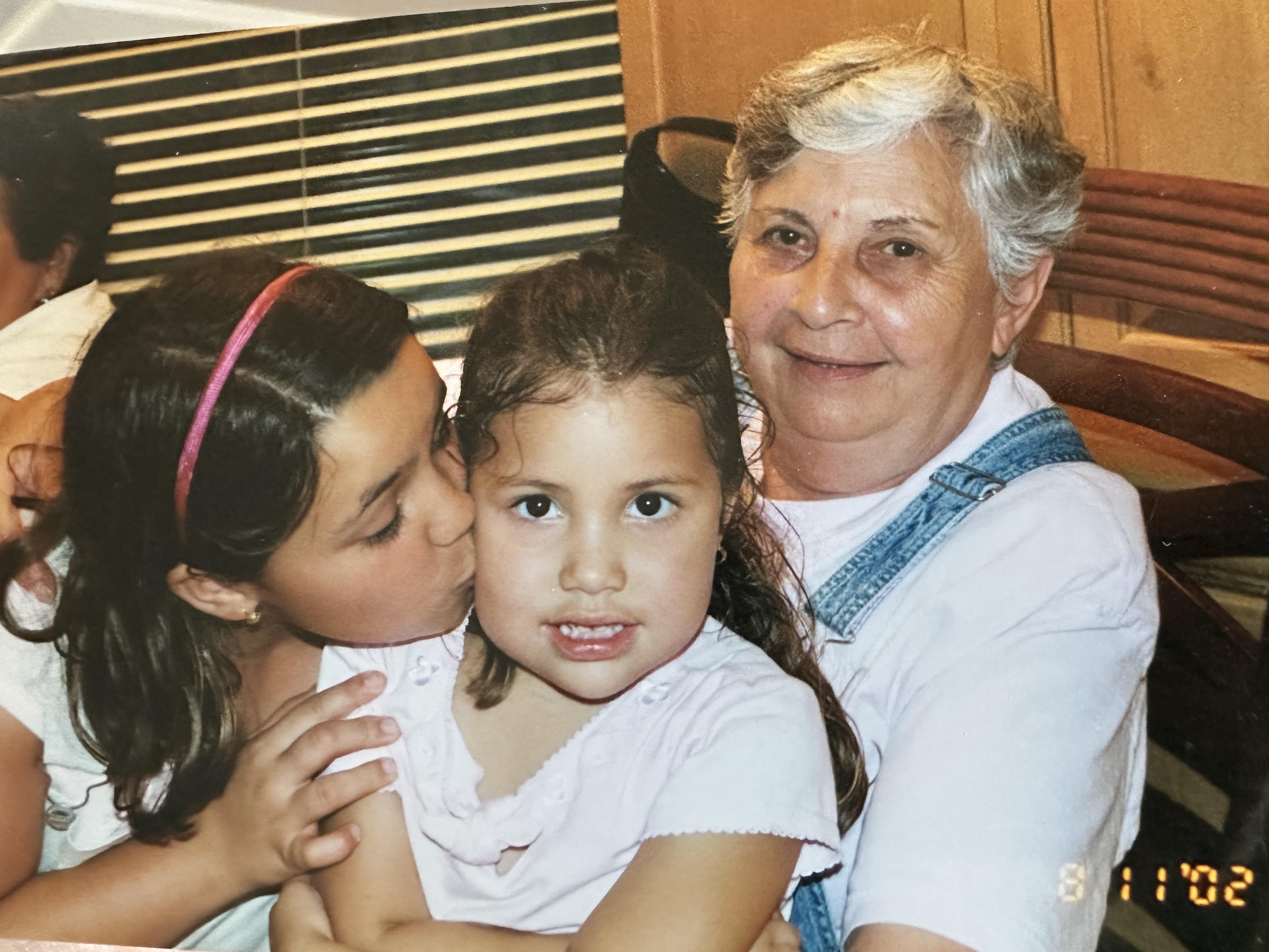 Two children embrace their grandmother during a joyful family gathering at home.