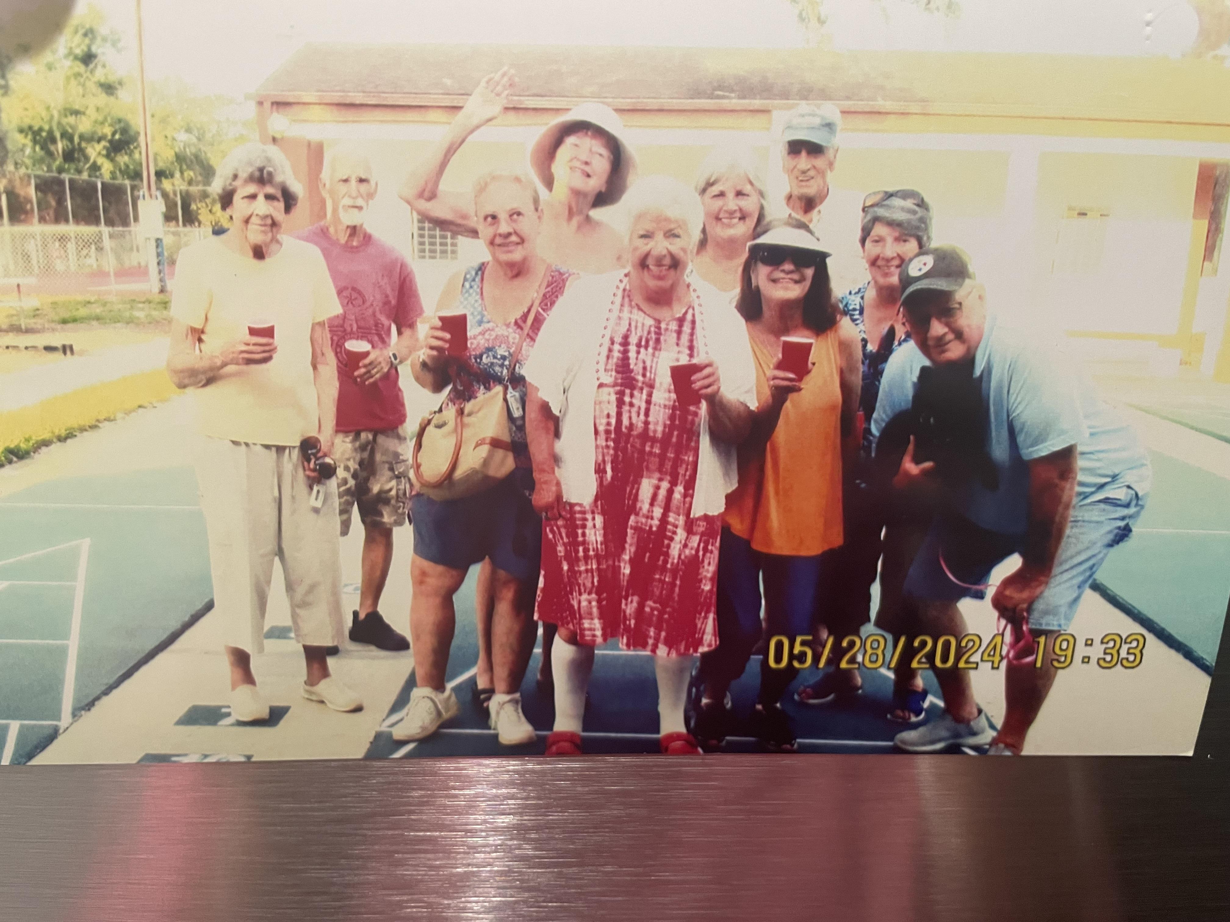 Seniors celebrate together outdoors, holding red cups and smiling at a community gathering.