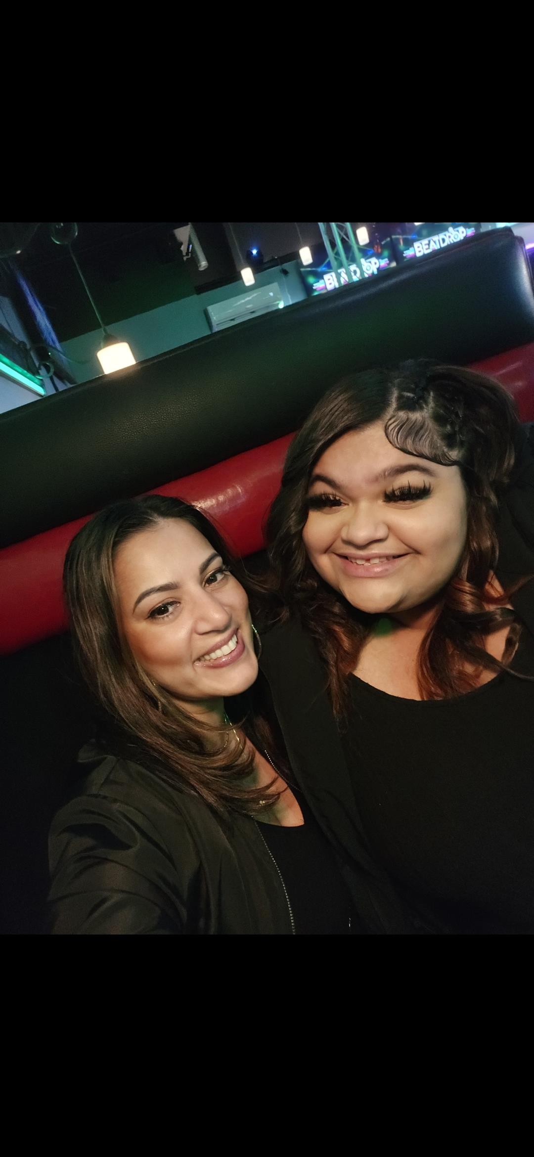 Two friends pose for a cheerful picture at a lively location, highlighting friendship and happiness.