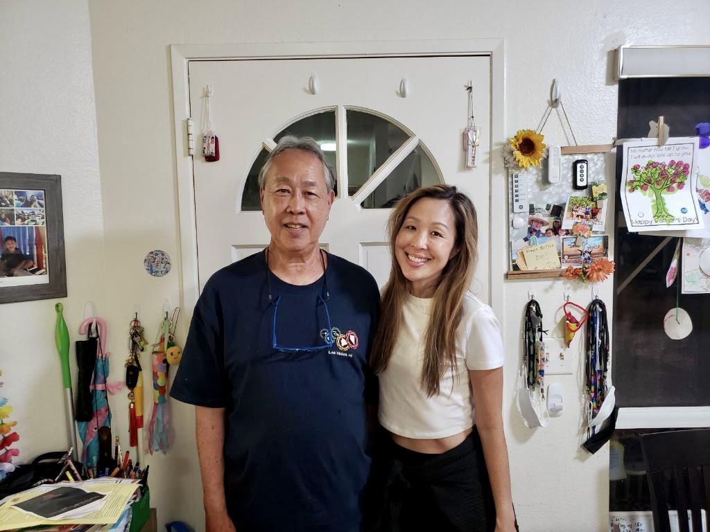 Two people pose together in a warm home environment, sharing a cheerful moment together.