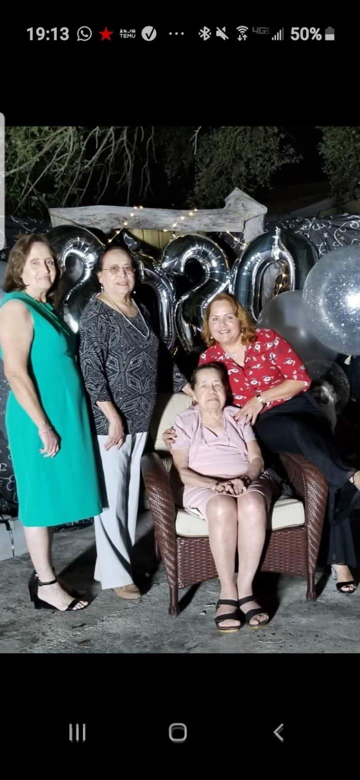 Four women gather joyfully at night, surrounded by festive decorations and balloons.