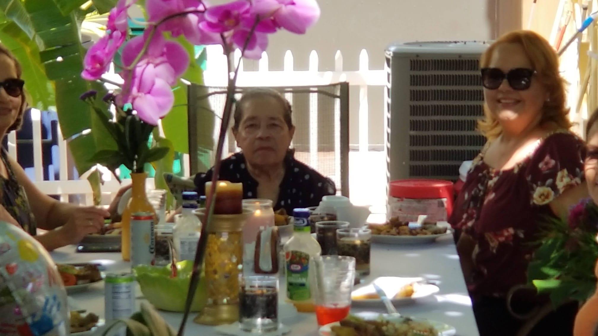 A lively family gathering takes place in a backyard, featuring delicious food and vibrant flowers.