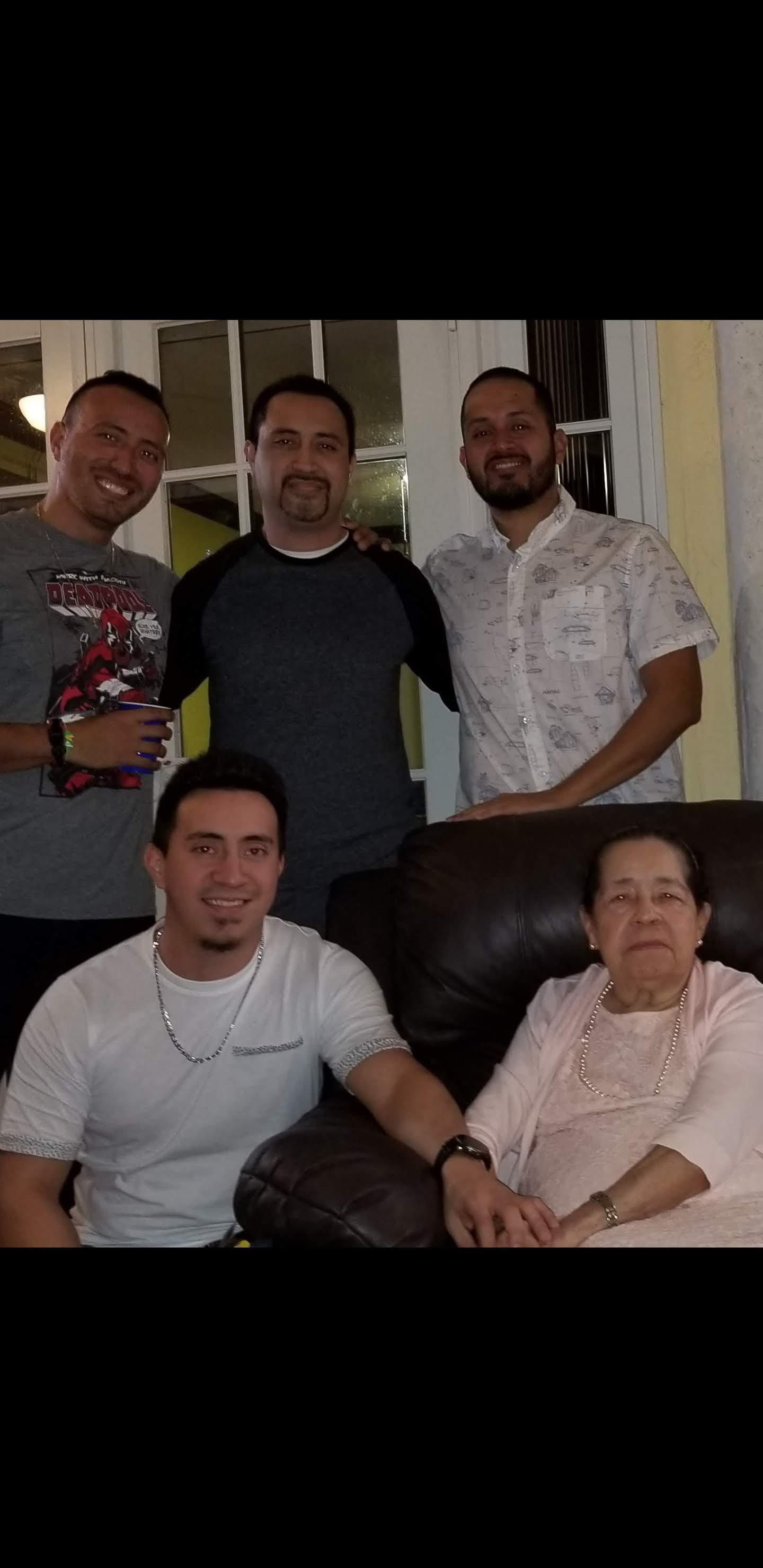 Five men pose happily with a woman in a comfortable living room during a family gathering.