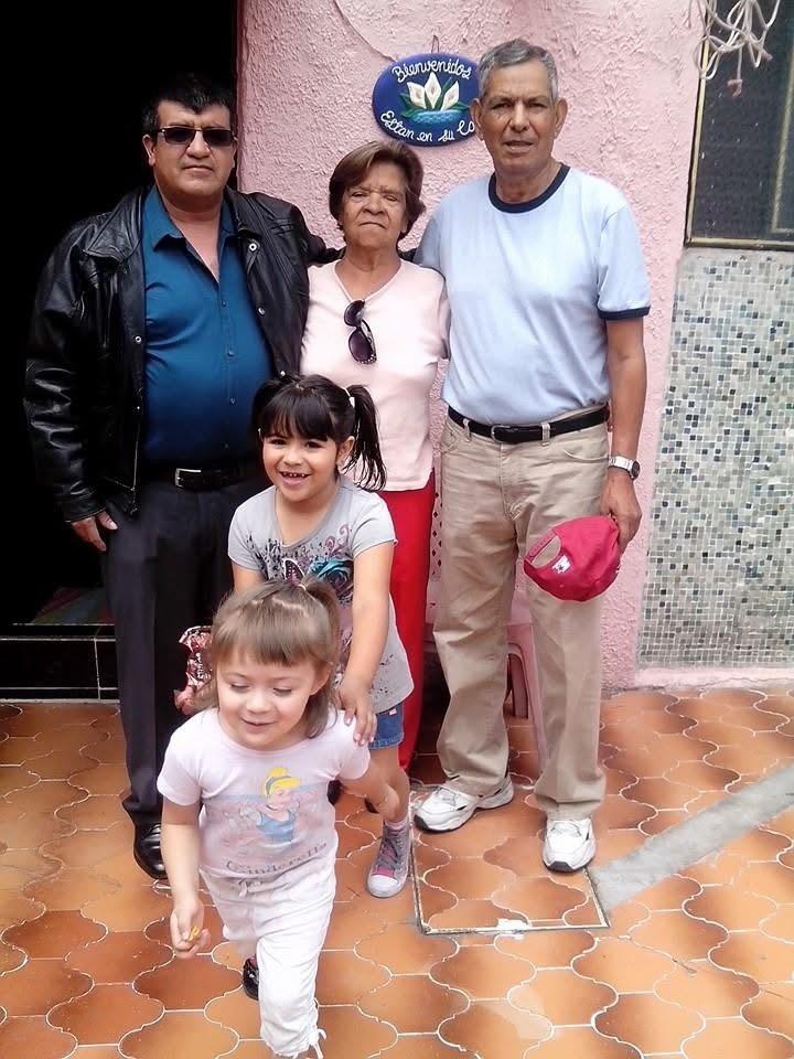 A cheerful family stands together as two young girls enjoy their time in a vibrant courtyard.