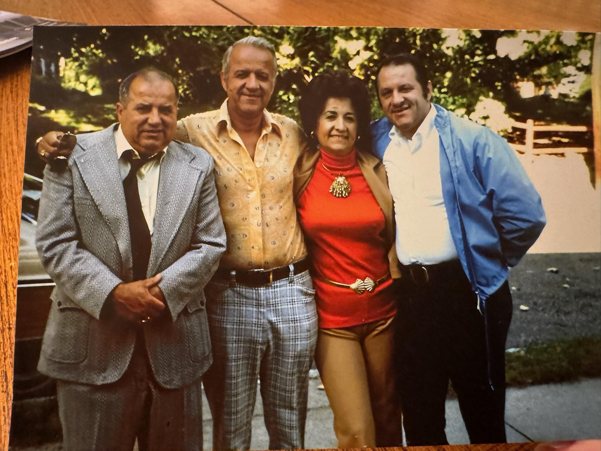Four friends pose together outdoors, showcasing stylish outfits typical of the 1970s.