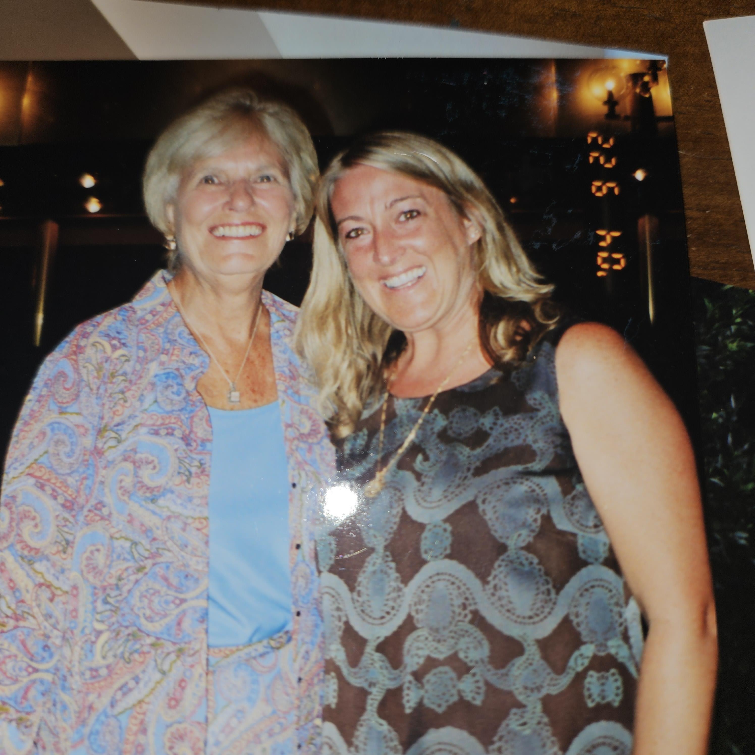 Two women share a joyful moment while celebrating at an indoor venue well into the evening.