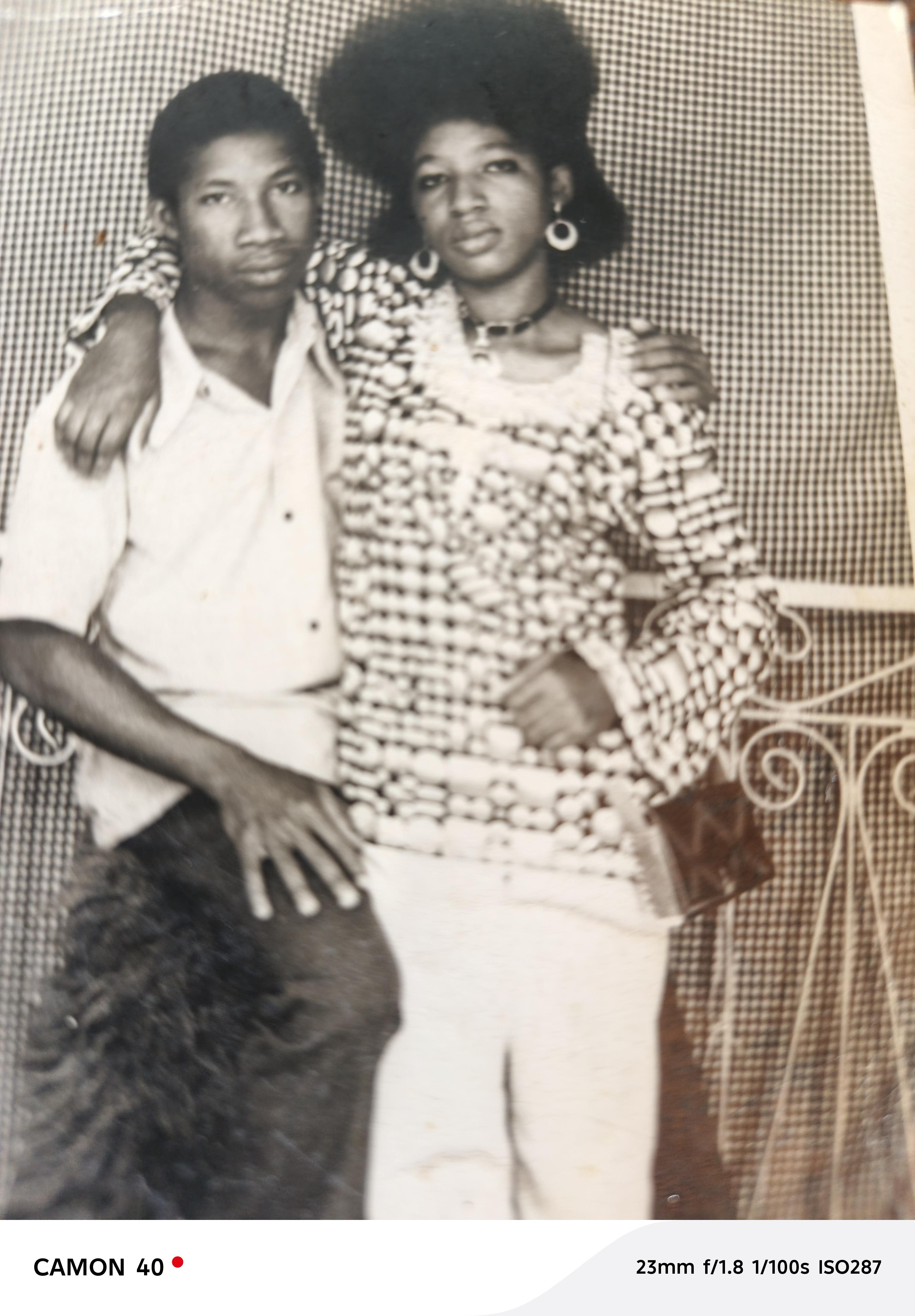 A stylish couple poses closely together, displaying their fashionable attire at a social gathering.