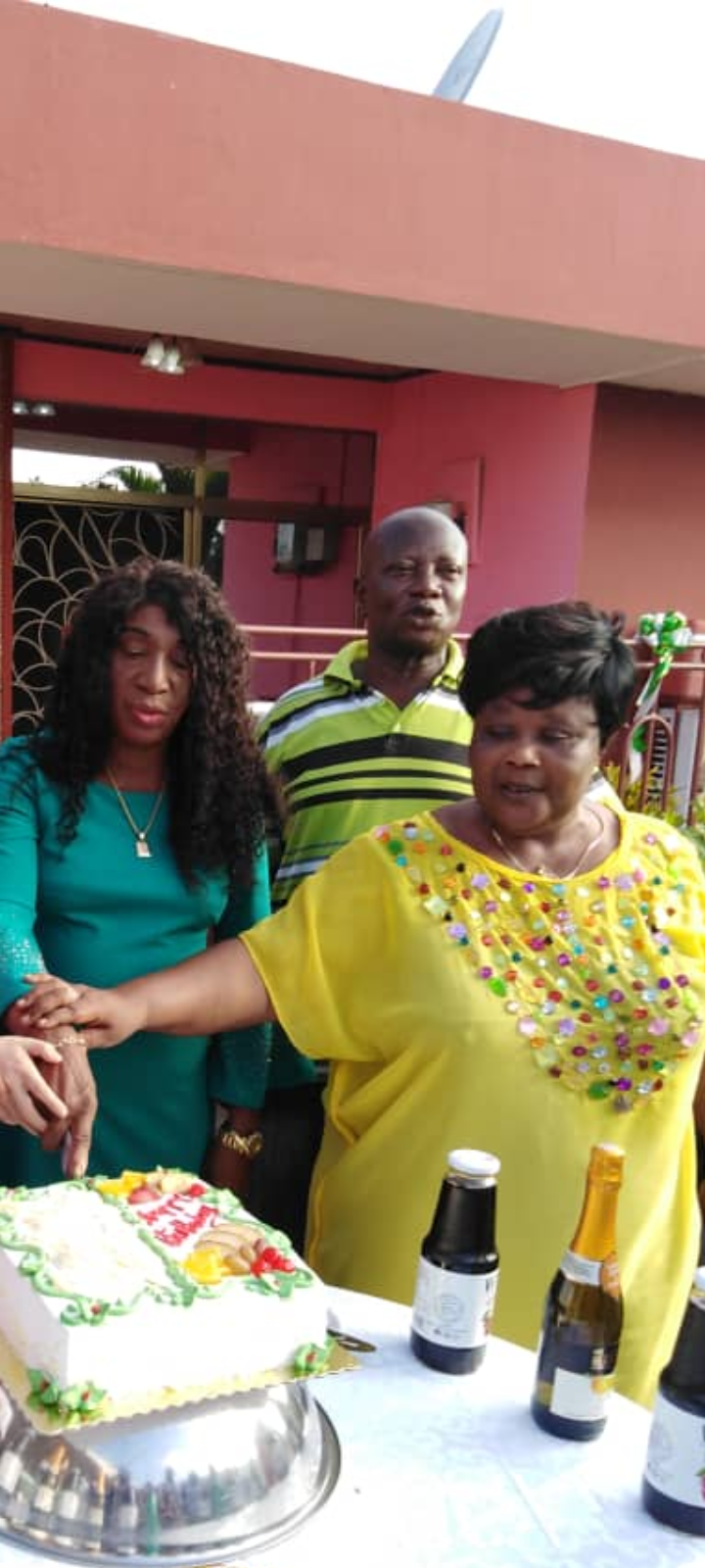 Family and friends gather to celebrate a birthday while surrounding a decorated cake and drinks.