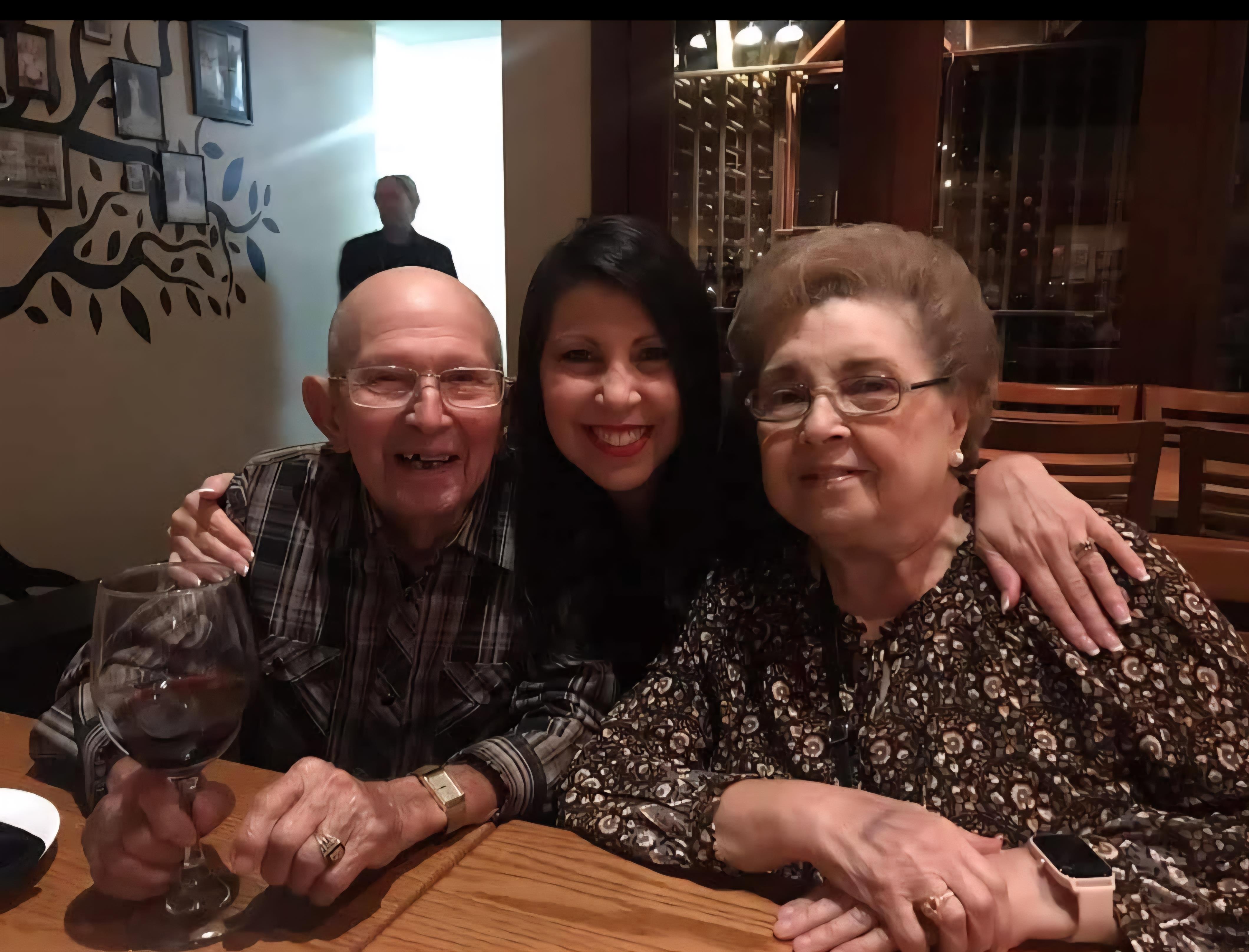 Three family members enjoy a warm evening together at a restaurant, sharing laughter and wine.