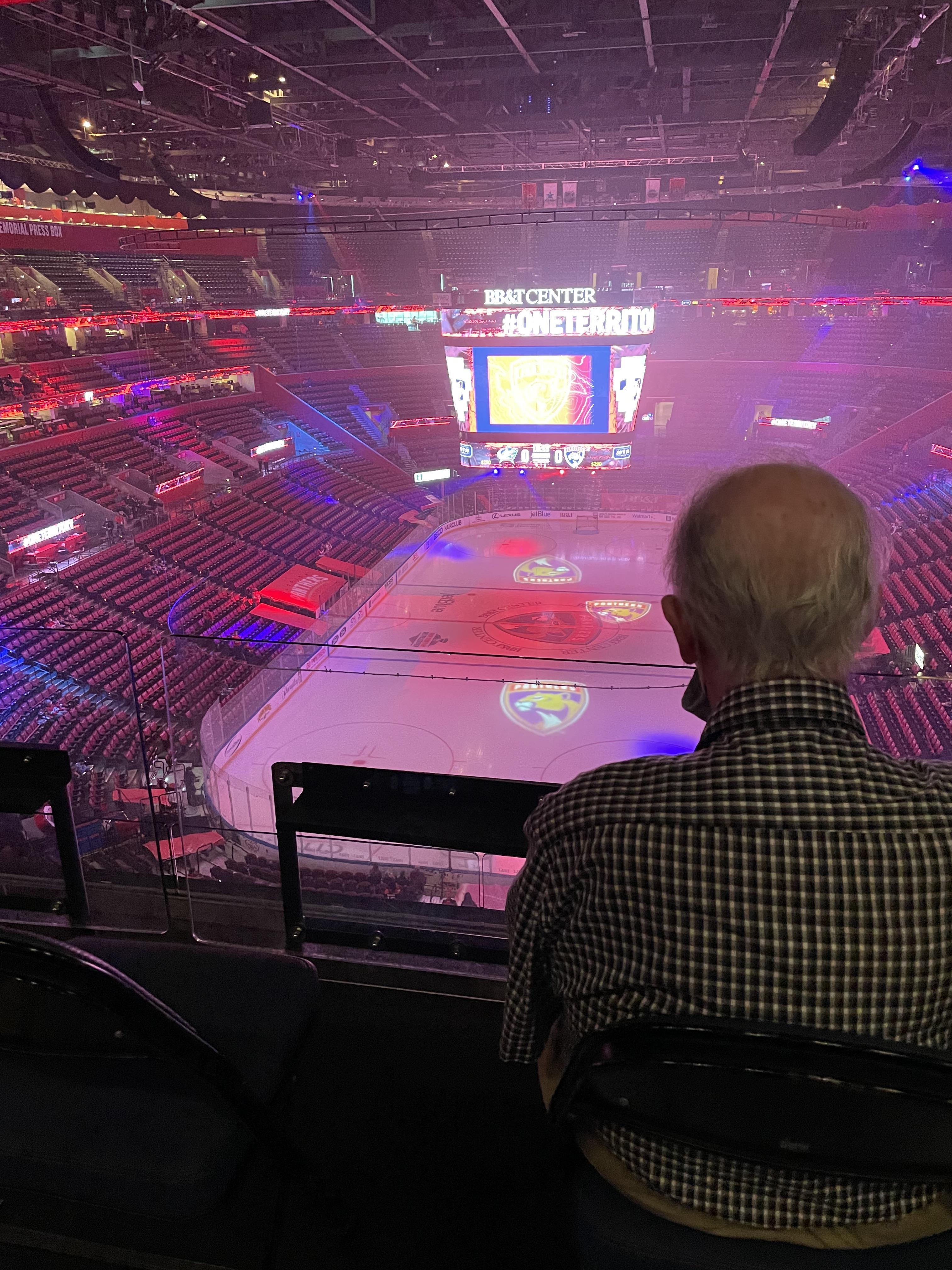 An elderly man sits quietly, observing the energetic pregame setup at BB&T Center.