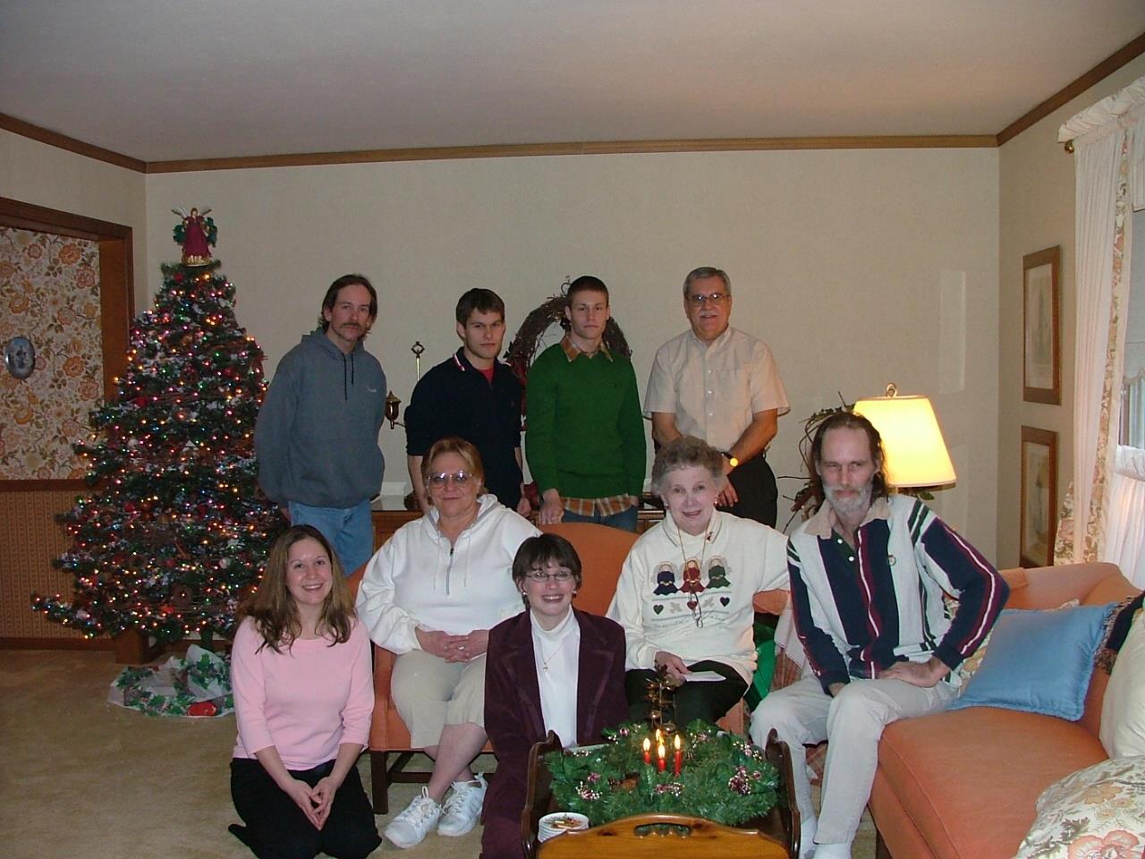 Family members joyfully pose together in a warm living room, celebrating Christmas time.