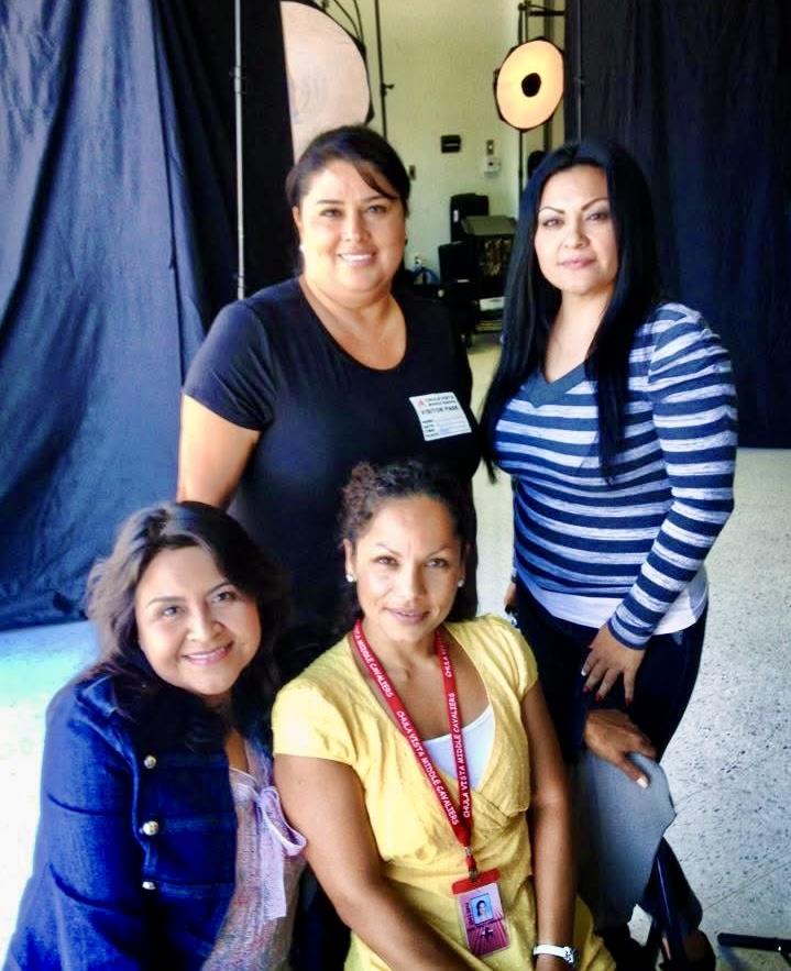 Four women smile and pose in a bright photography studio, enjoying a creative moment together.