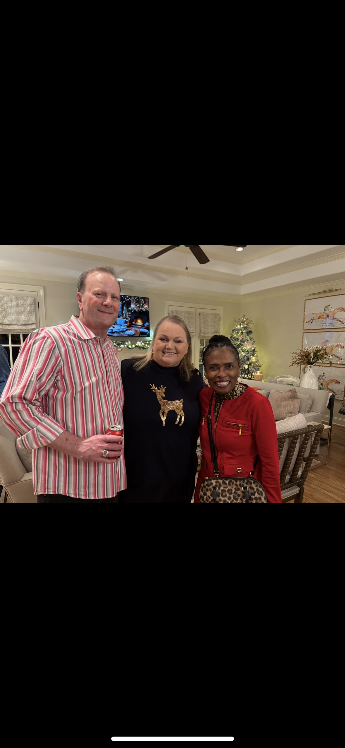 Three friends enjoy each other's company in a warm, inviting living room decorated for the holidays.