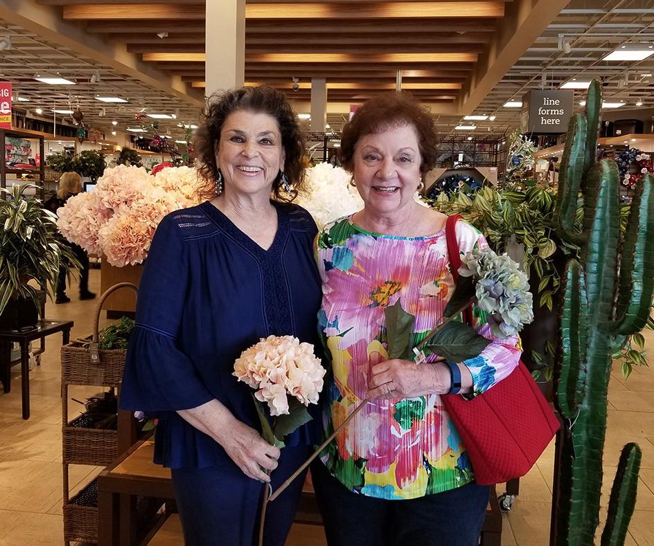 Women enjoy a cheerful moment at a floral shop, surrounded by colorful blooms and greenery.