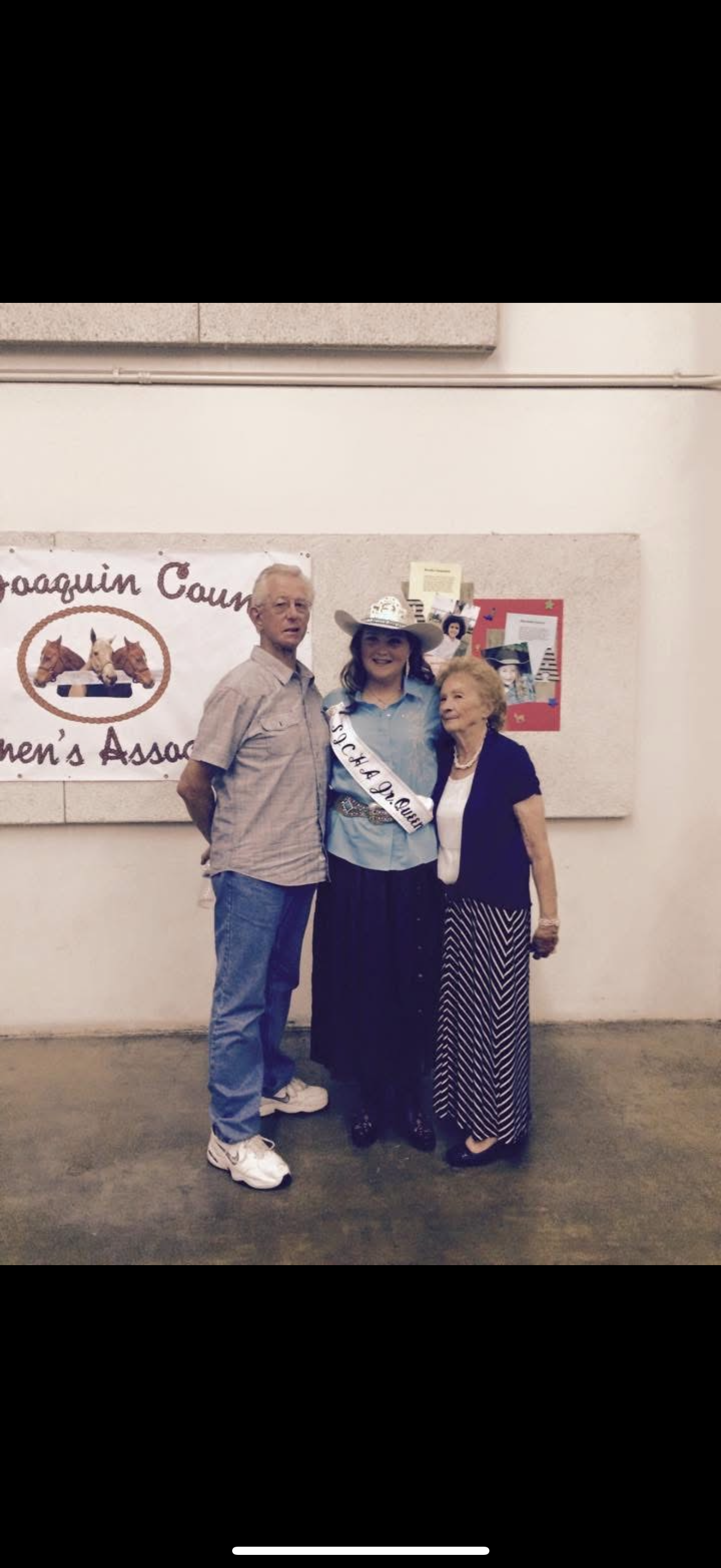Three individuals smile together during a community event in a county hall, celebrating connections.