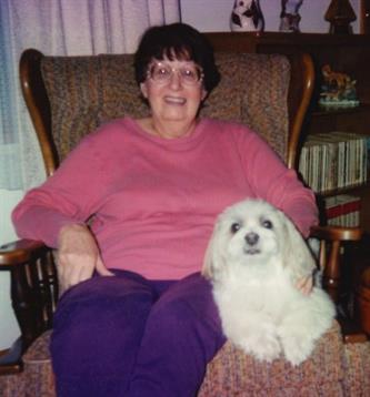 Warm moment shared between a smiling woman and her fluffy dog while sitting in an armchair.