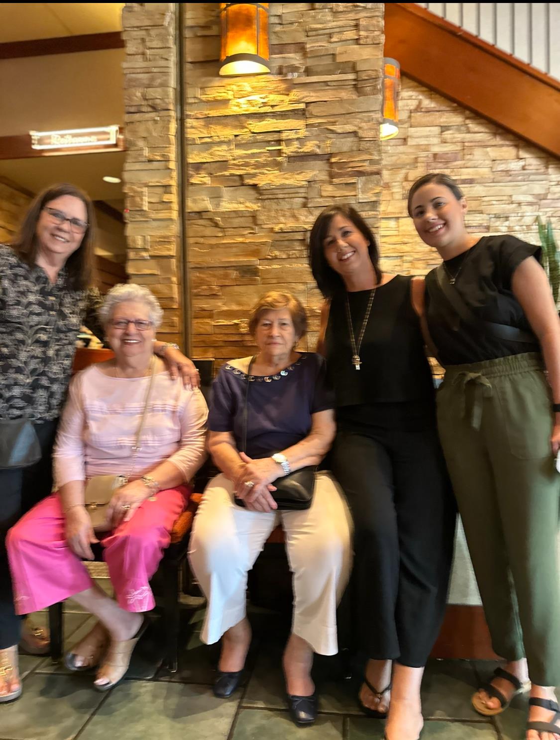 Five women of different ages pose together in a restaurant, highlighting family connections.