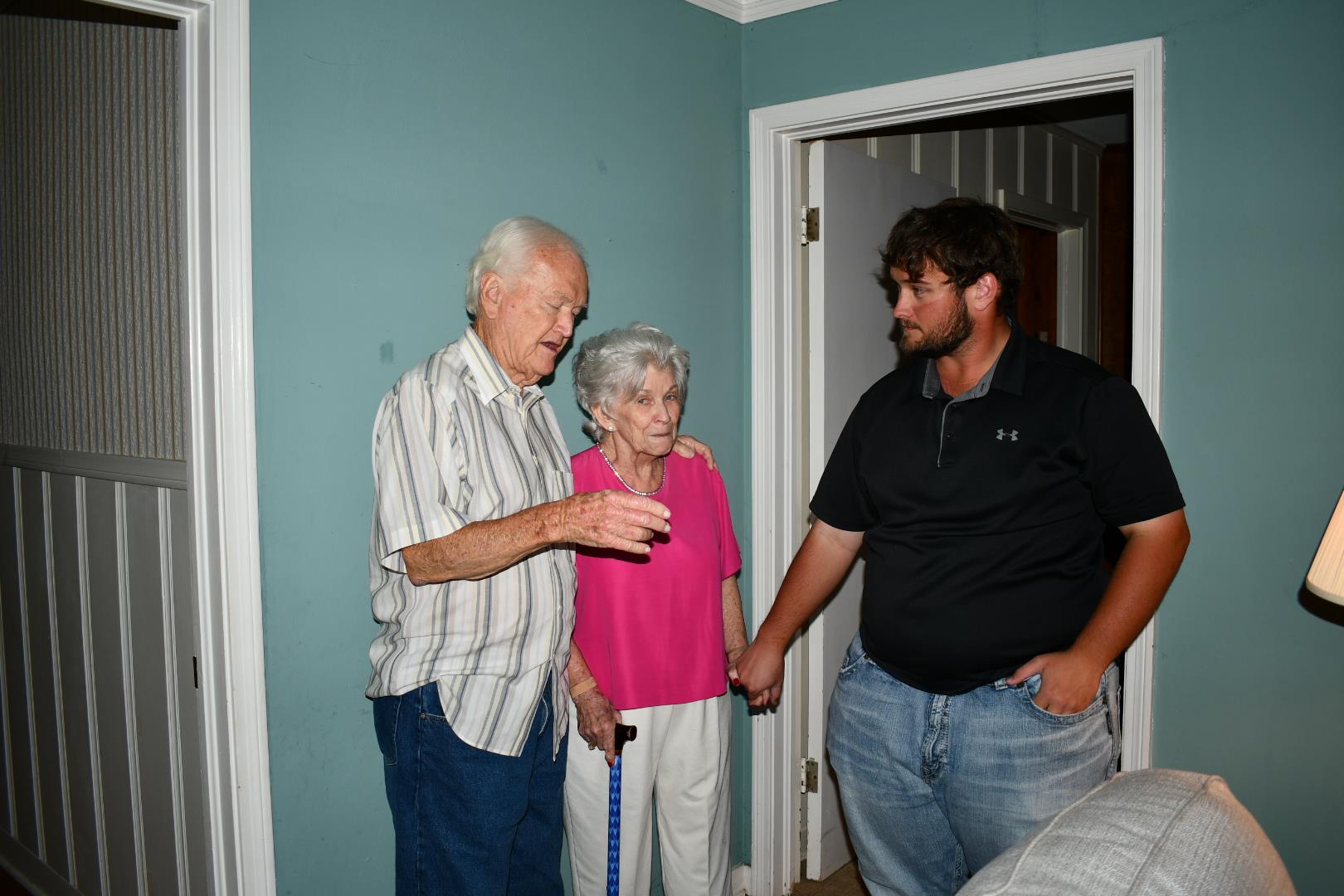 Three family members engage in a heartfelt conversation in the living room of a home.