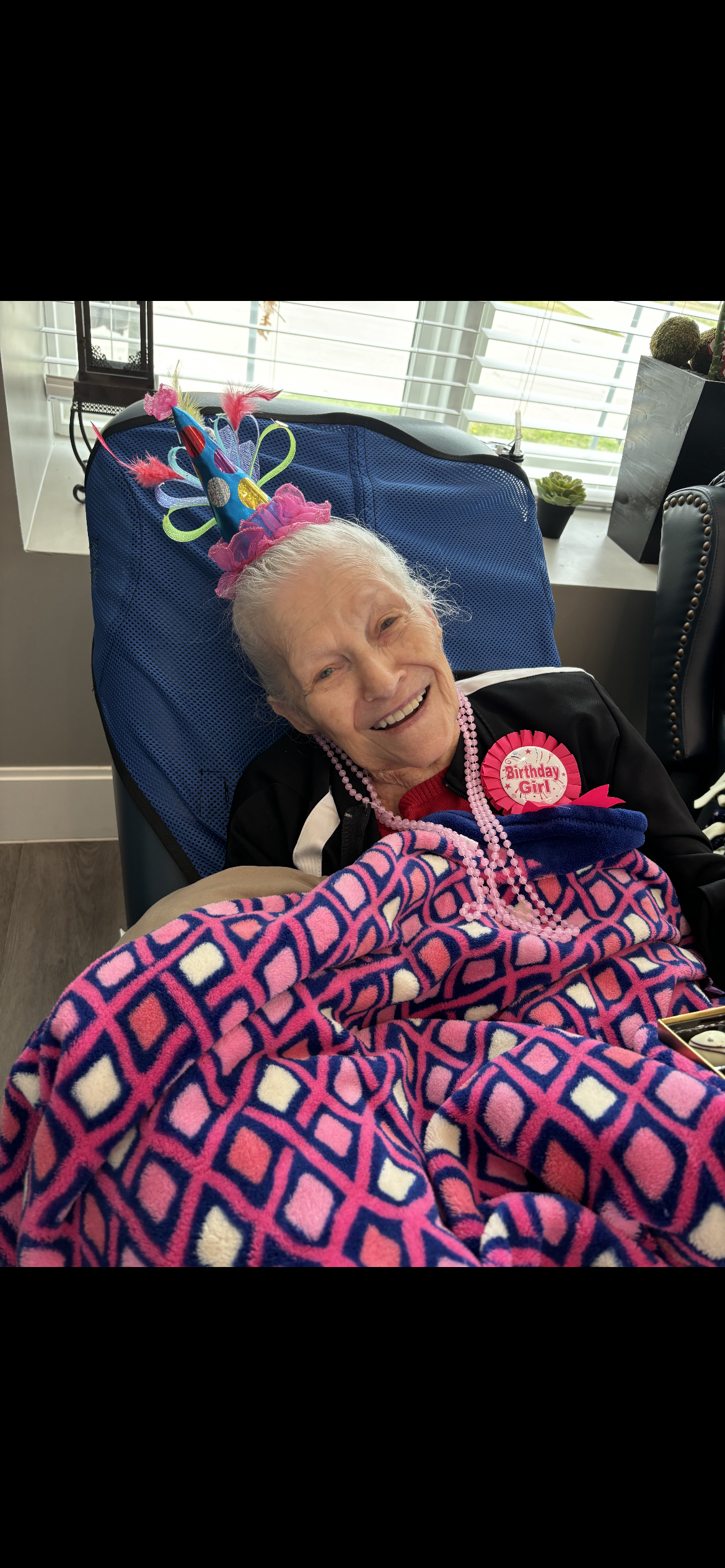 An elderly woman enjoys her birthday surrounded by family in a warm, inviting atmosphere.