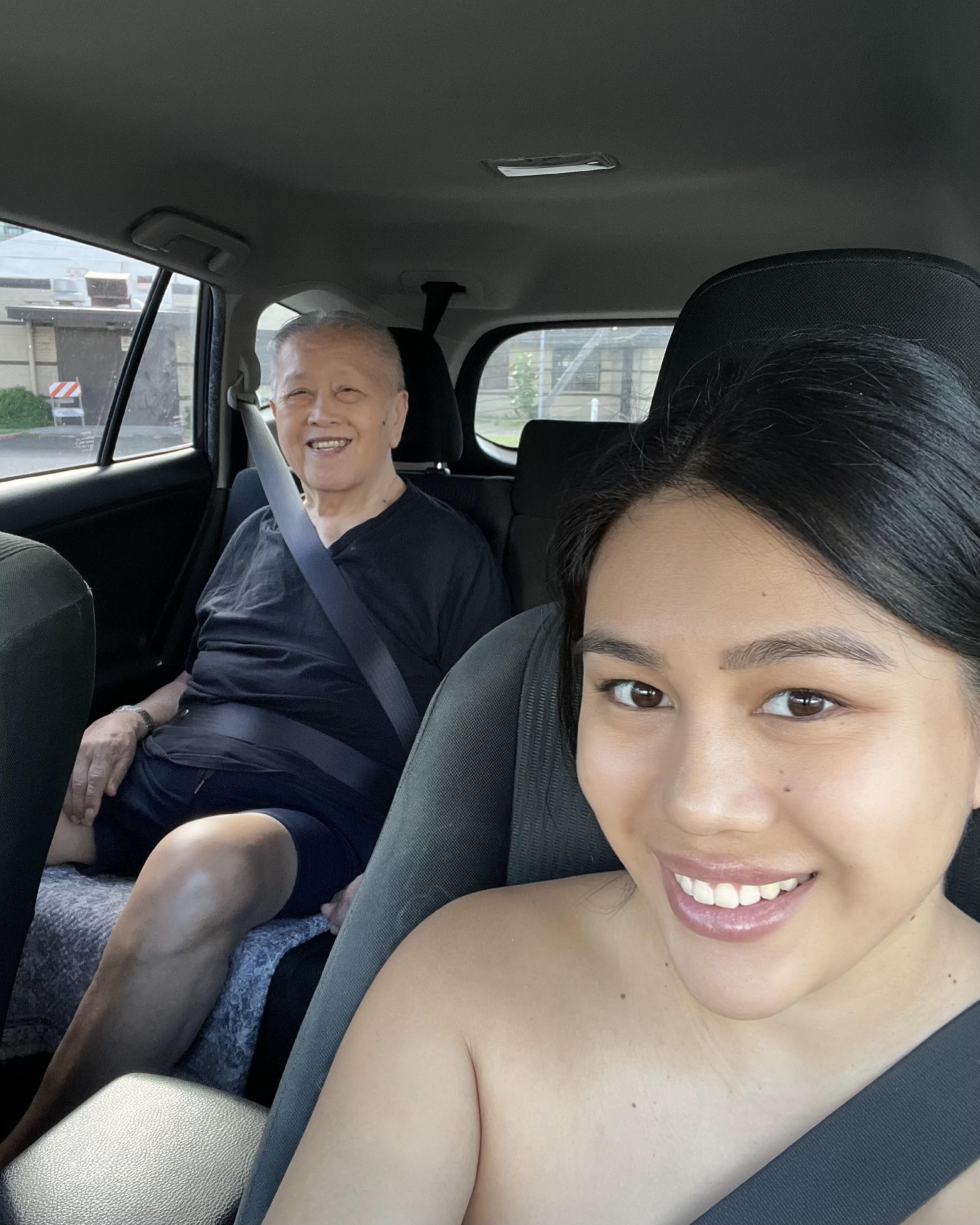 Young woman enjoys a cheerful moment in the car with an elderly man, both smiling happily.