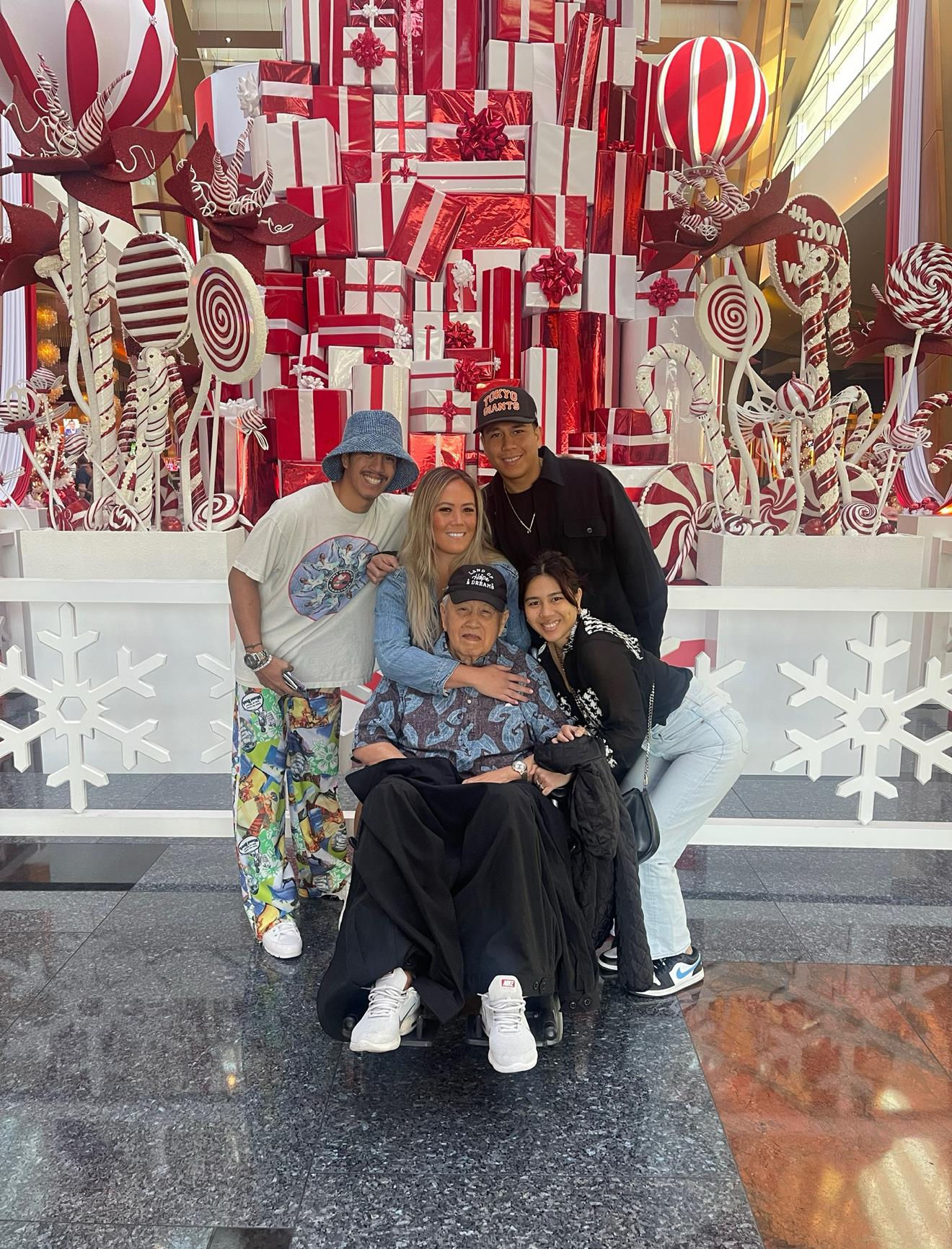 Group of family members poses together, celebrating the holiday season in a vibrant shopping area.