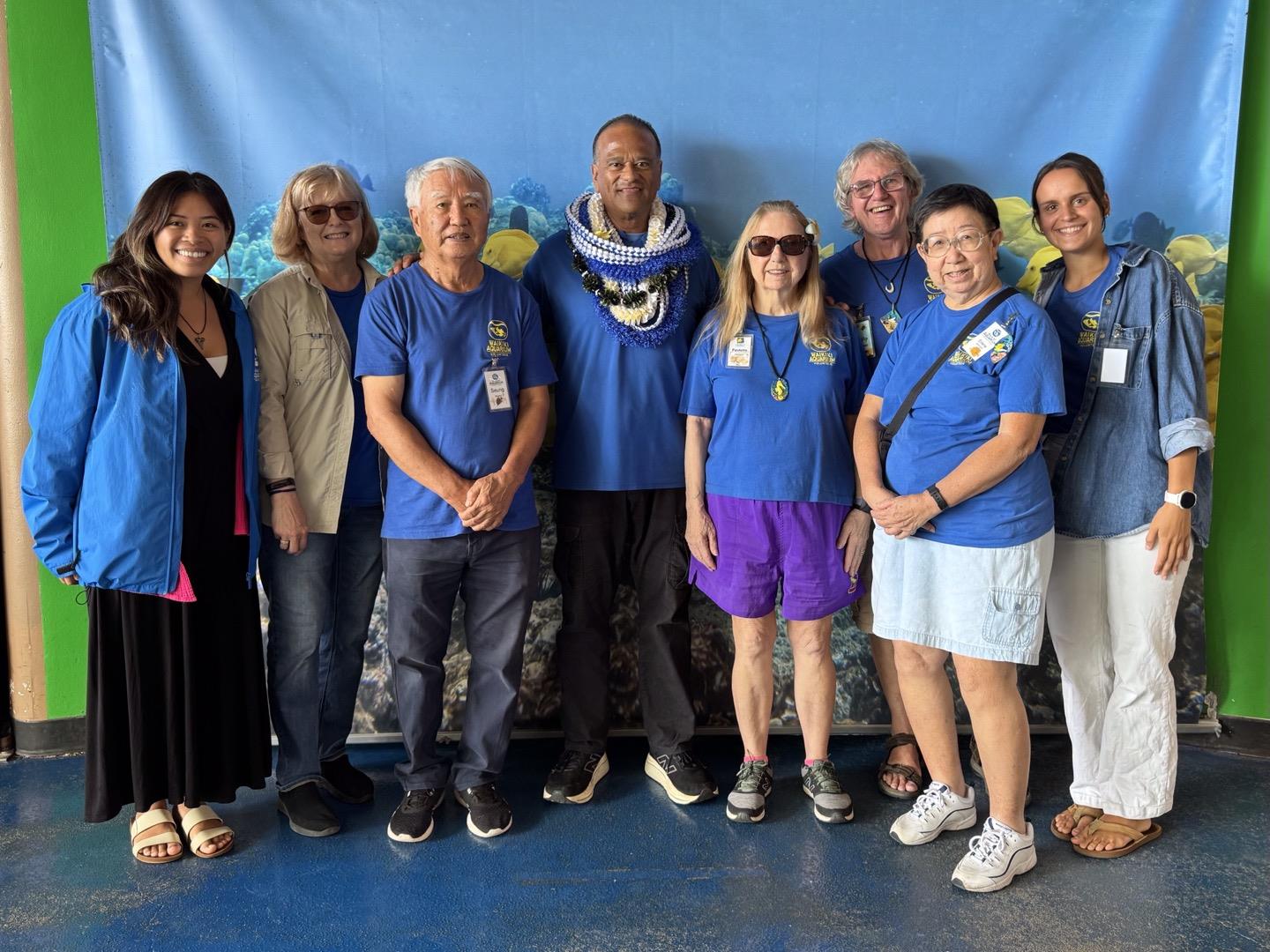 Volunteers engage in a community event, posing in matching shirts with an underwater theme.