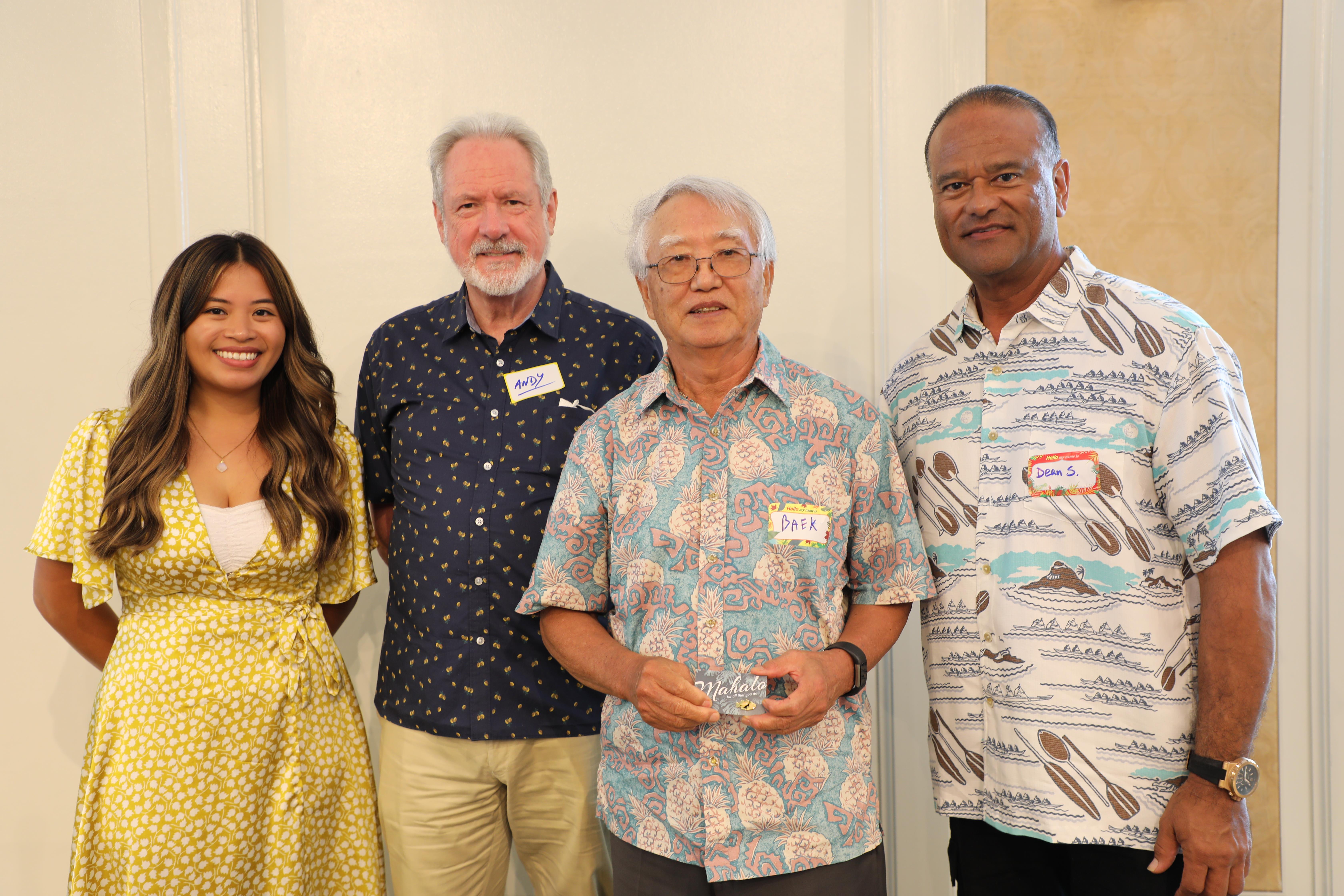 Four individuals stand together in a cheerful atmosphere, enjoying a social event indoors.