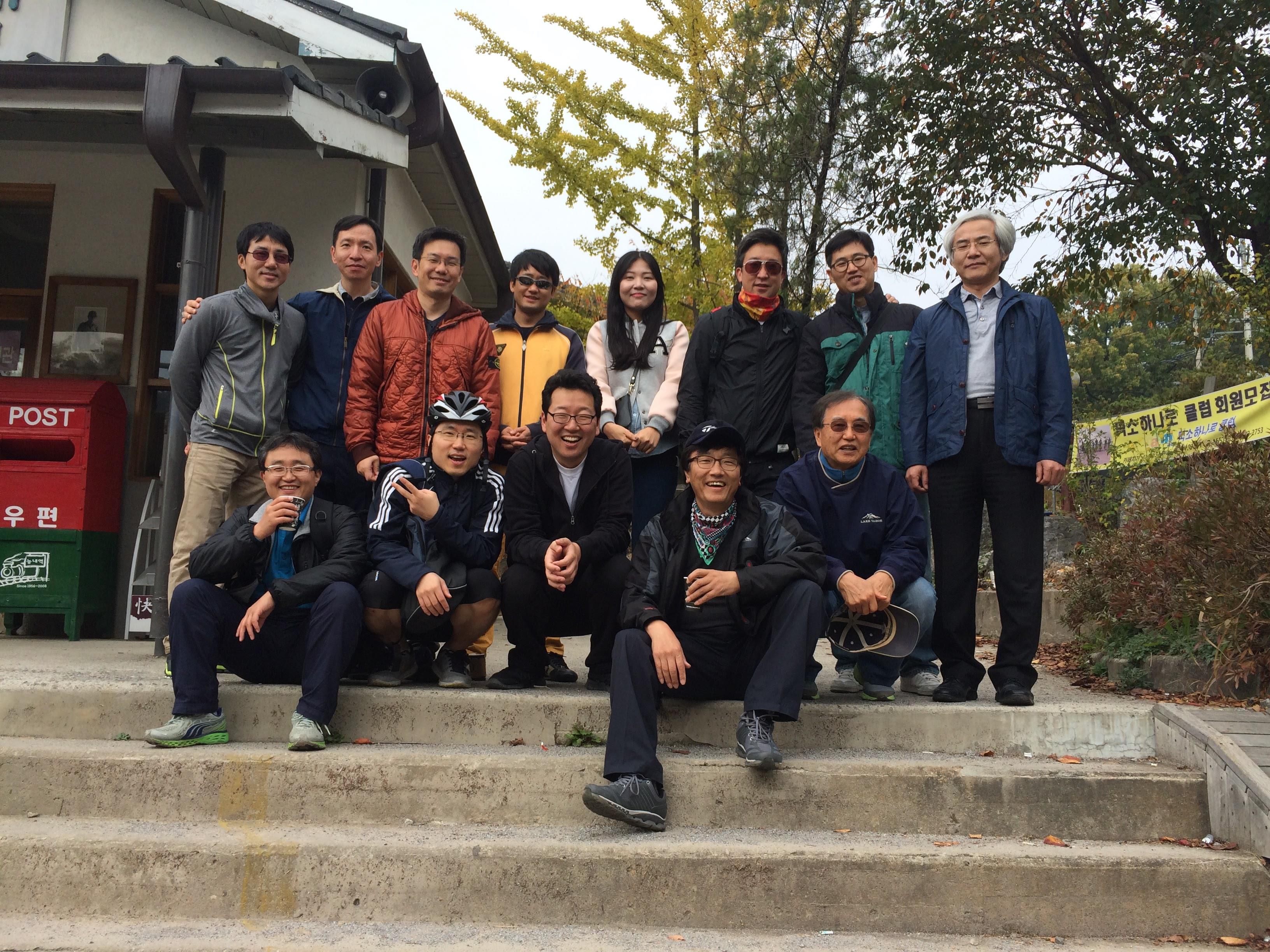 A large group of friends smiles and poses together outdoors, enjoying a crisp autumn day.