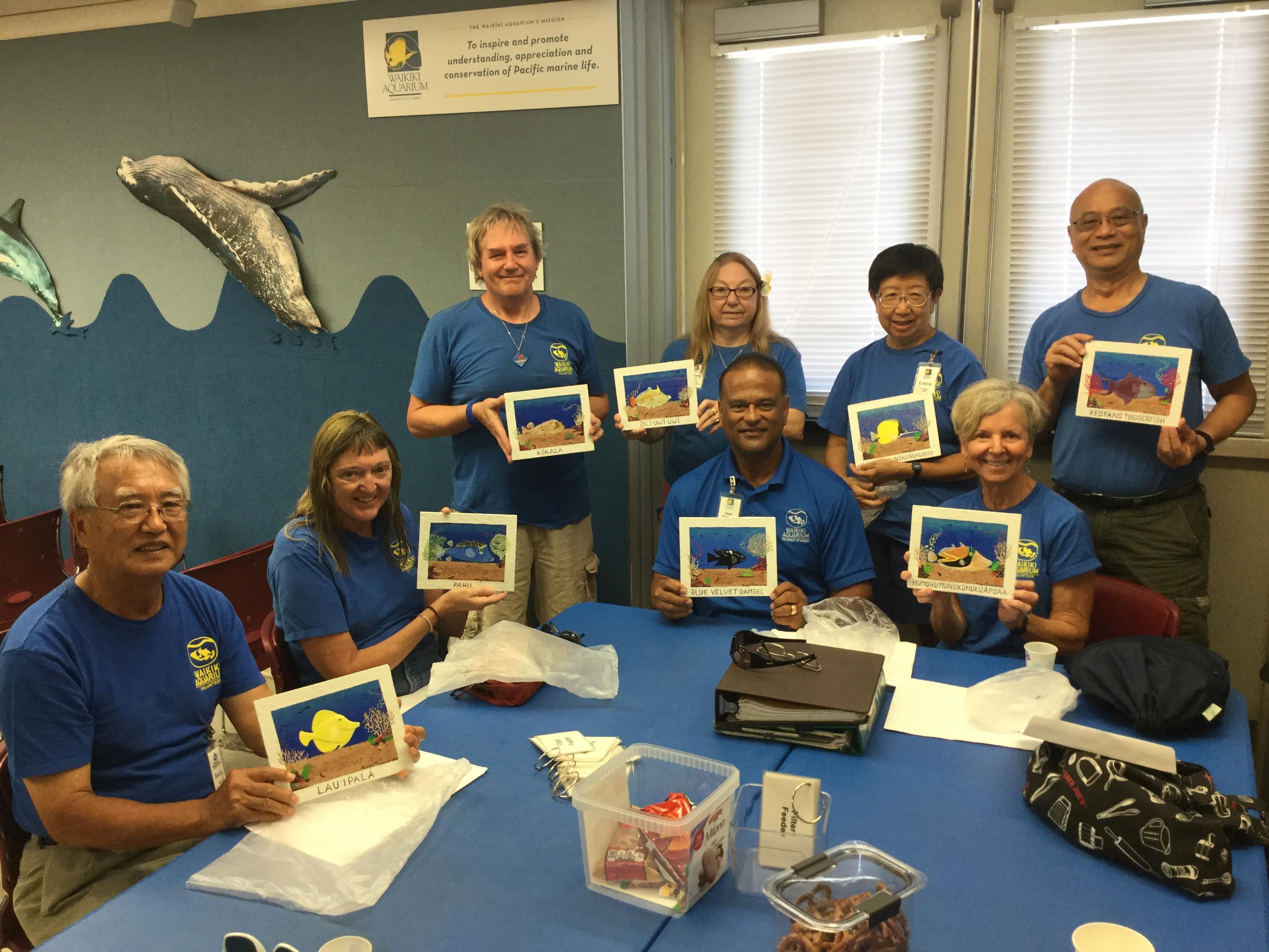 Participants display vibrant marine artwork from a creative workshop, highlighting teamwork.