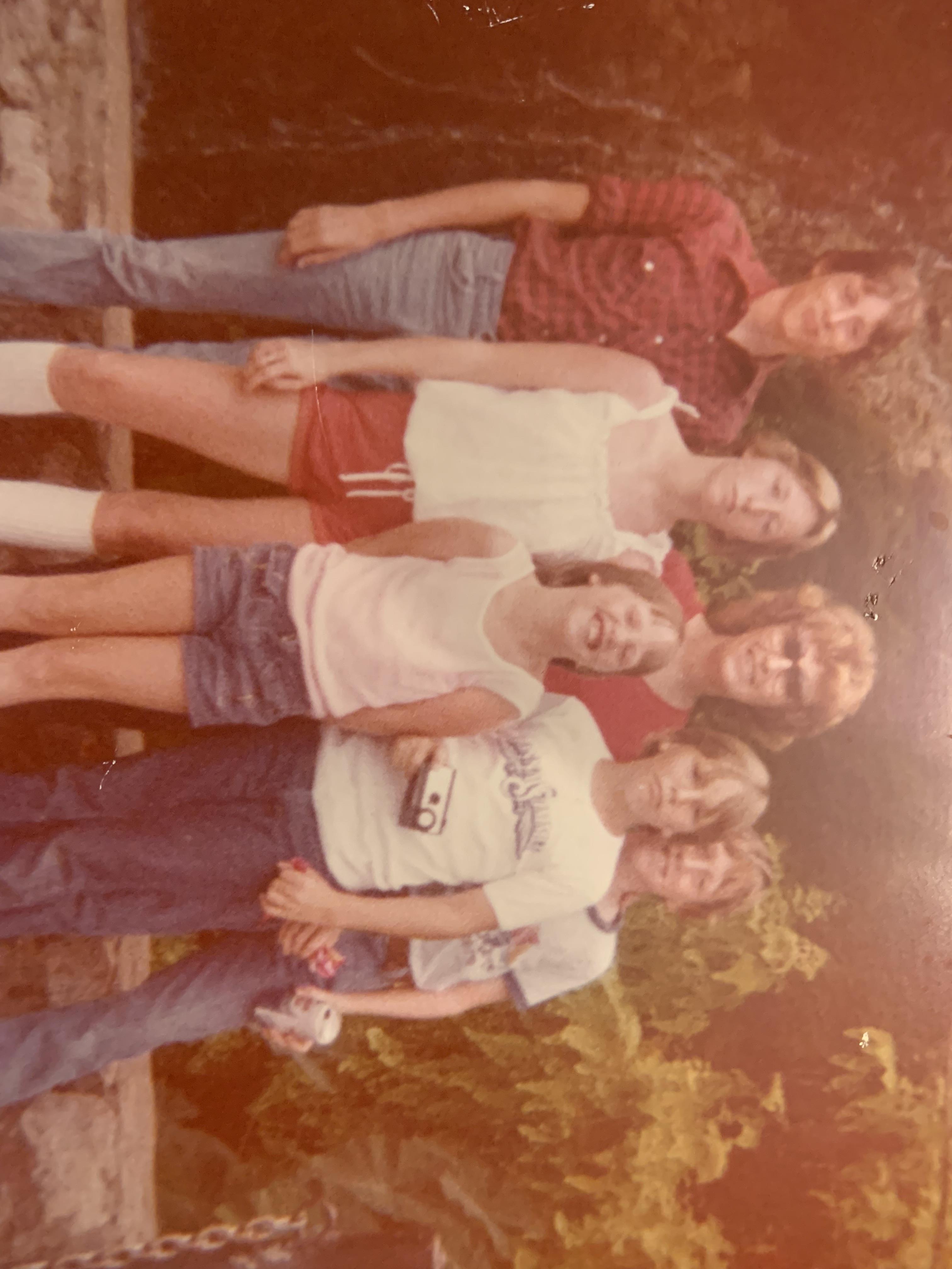 Friends gather in a park-like area, smiling and posing for a fun outdoor memory during summer days.