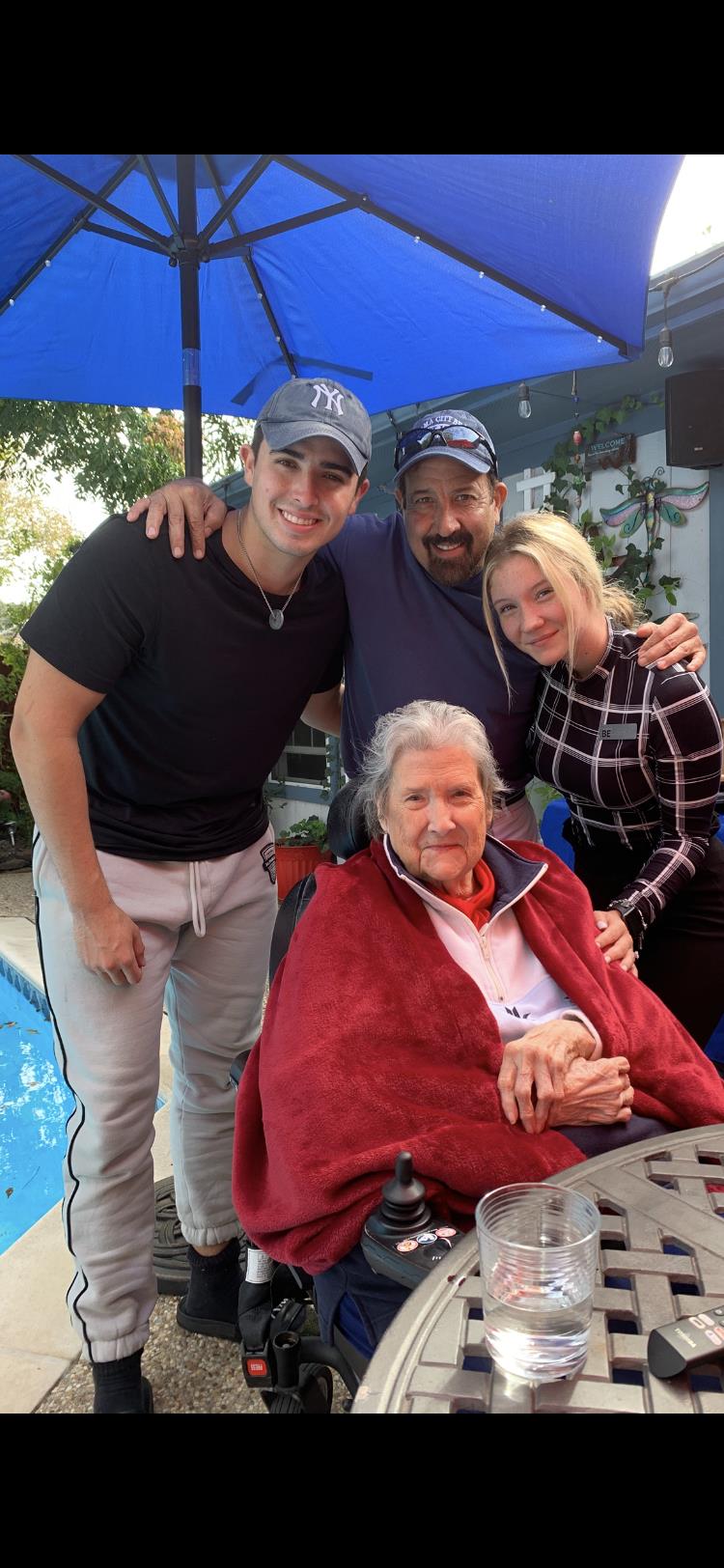 A group of four family members enjoys a joyful moment outdoors by the pool, celebrating together.