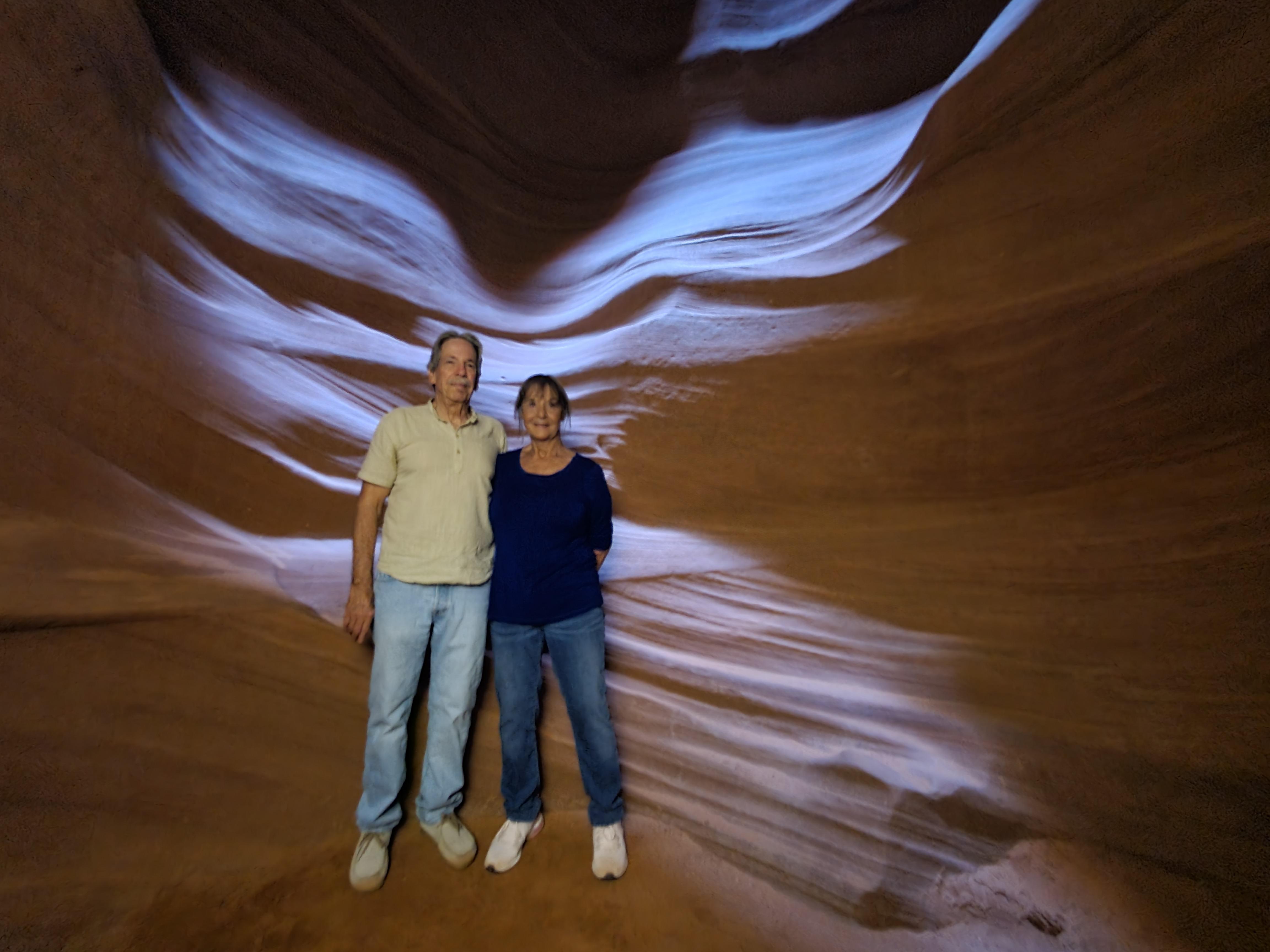 A couple stands side by side, captivated by the swirling sandstone formations and shadowy hues.
