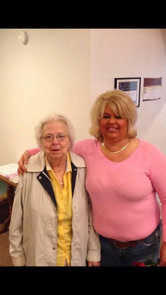 Two women pose together in a cozy indoor environment, sharing a joyful moment.
