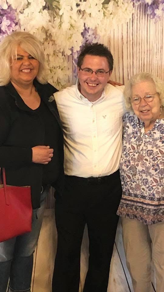 Three people stand together, smiling and enjoying a family gathering, showcasing their happiness.