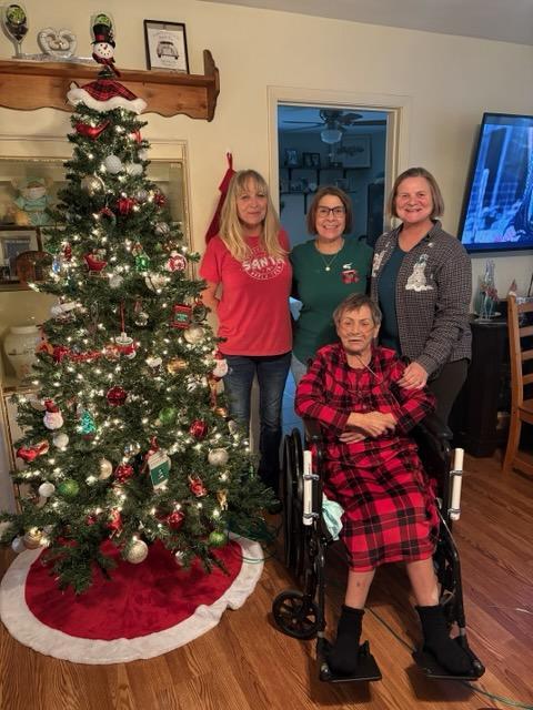 Four family members share joyful moments near a beautifully decorated Christmas tree.