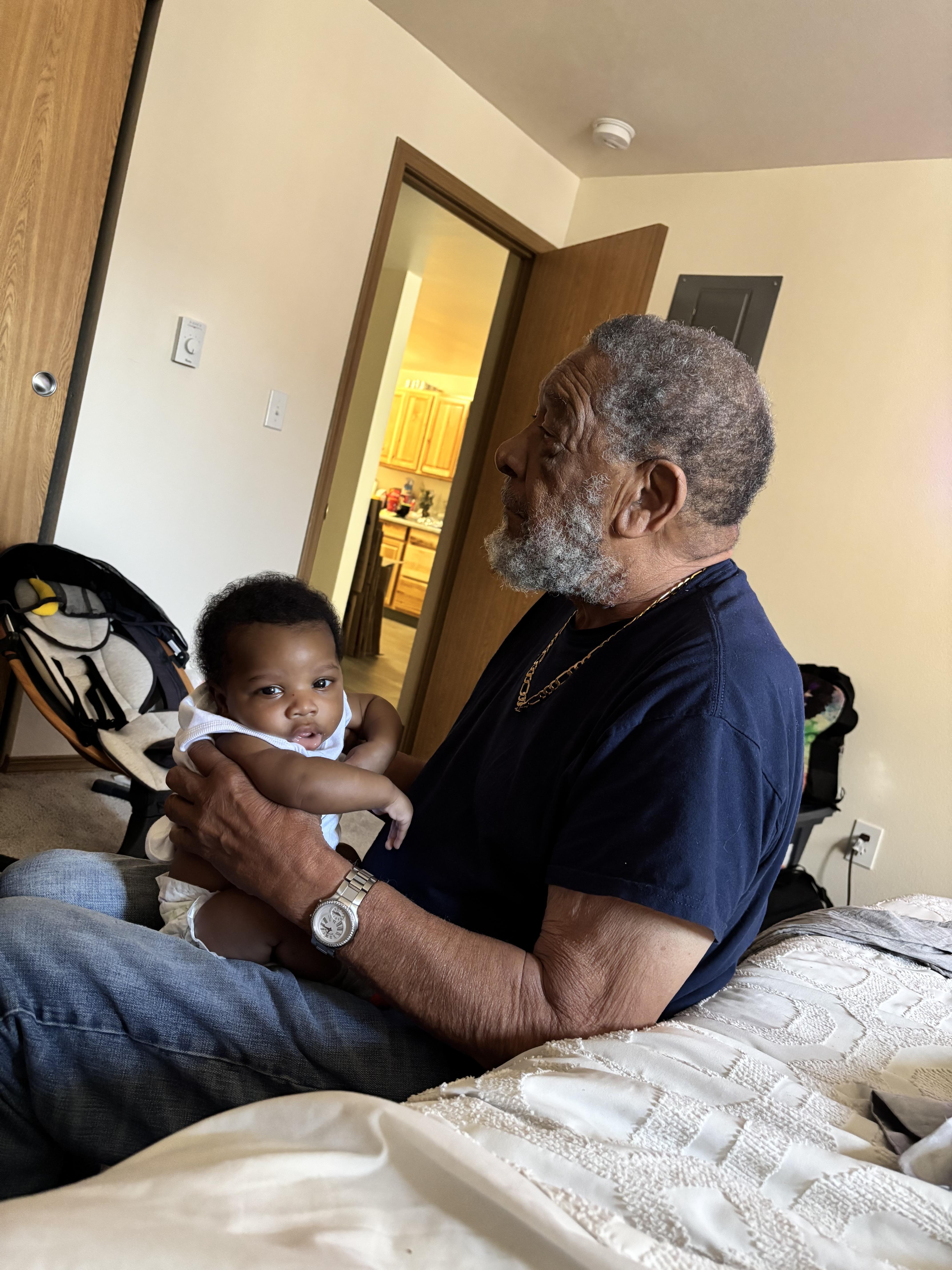 A man gently cradles a baby in a warm, inviting living room filled with soft natural light.