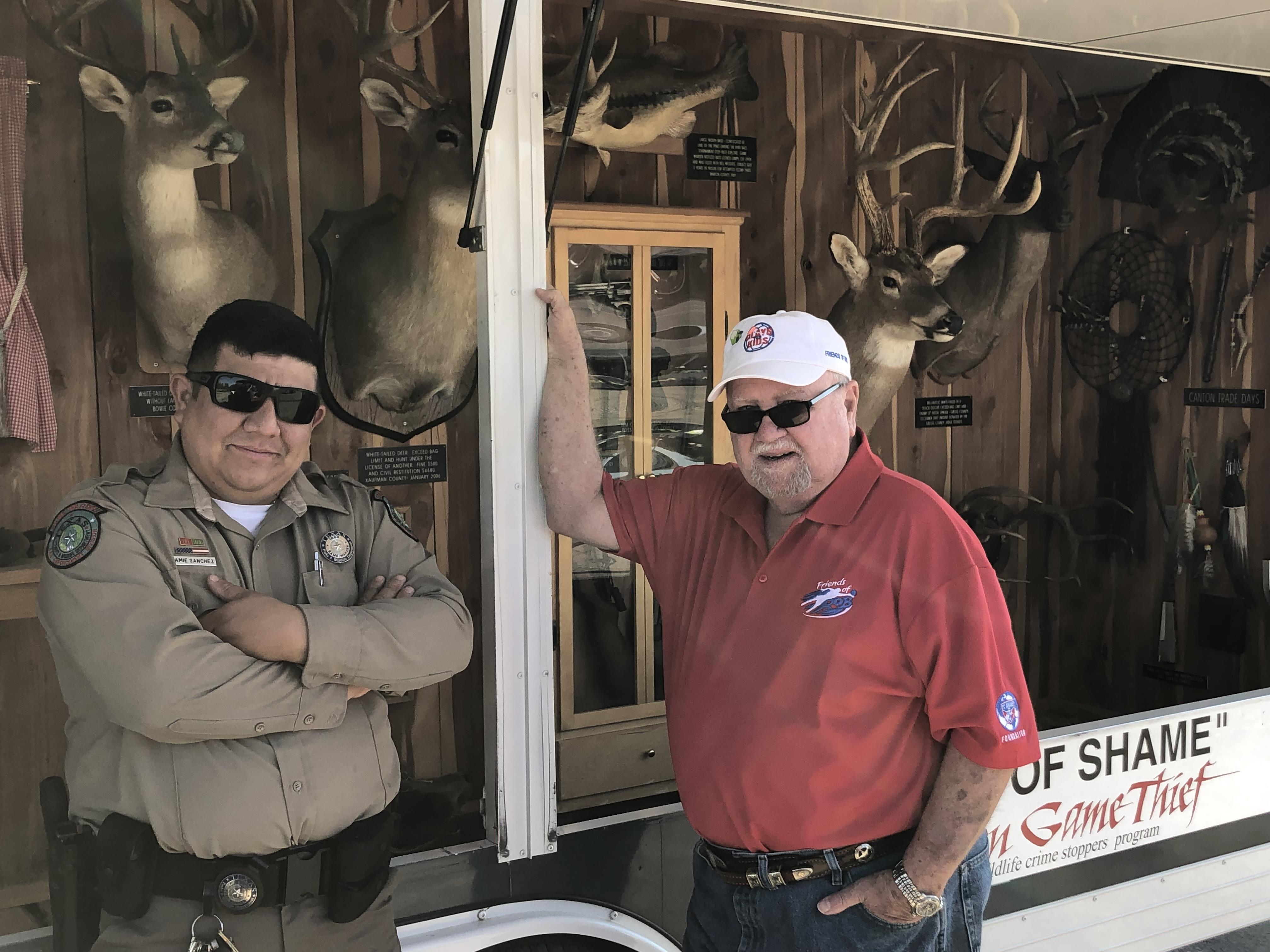 Officers address poaching at a community gathering, showcasing recovered animal trophies.